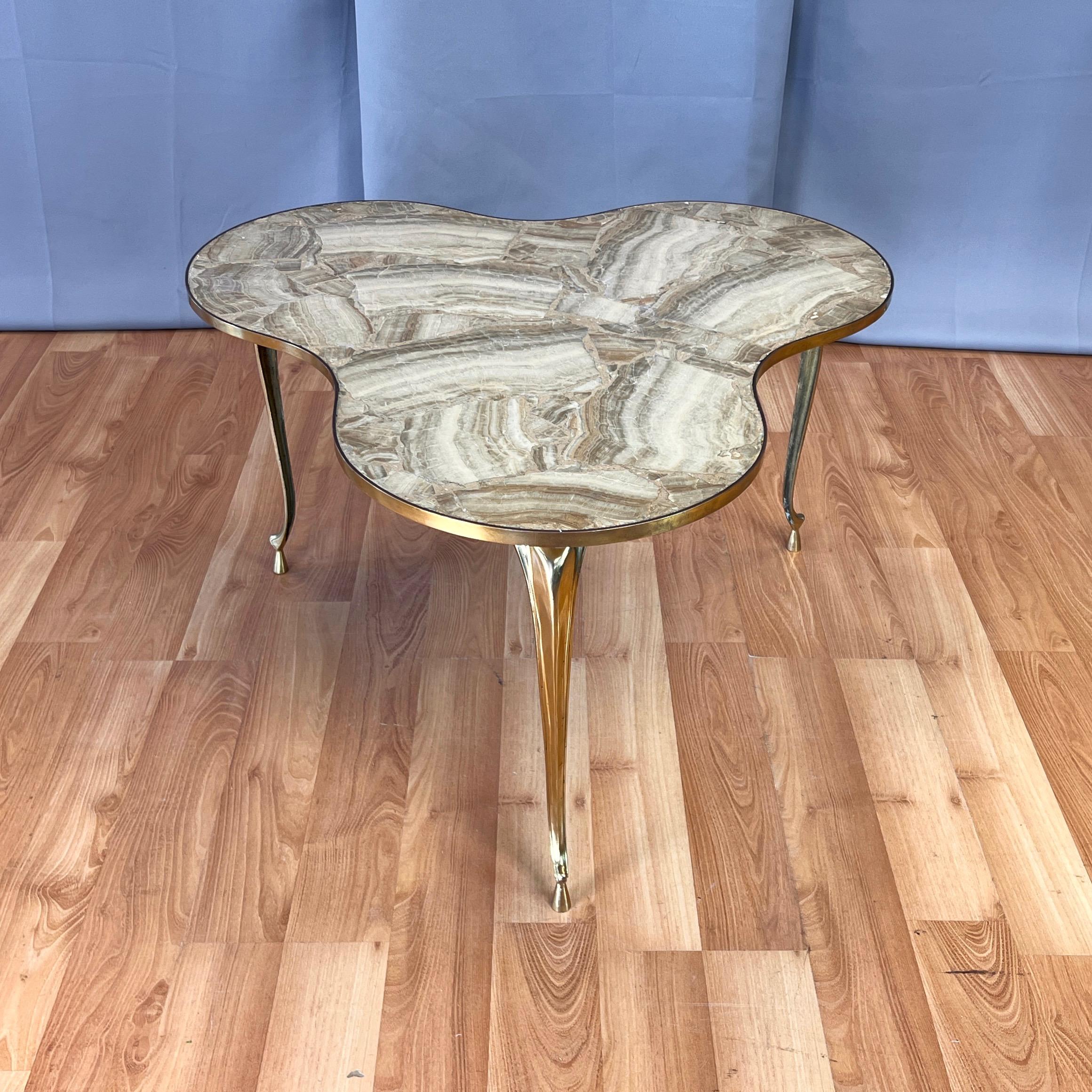 Ein auffälliger und seltener italienischer dreibeiniger Beistelltisch oder Beistelltisch aus Onyx und Messing aus den 1950er Jahren.

Die stilisierte dreiflügelige Platte mit anmutigen Kurven, die die drei Lappen miteinander verbinden, ist mit