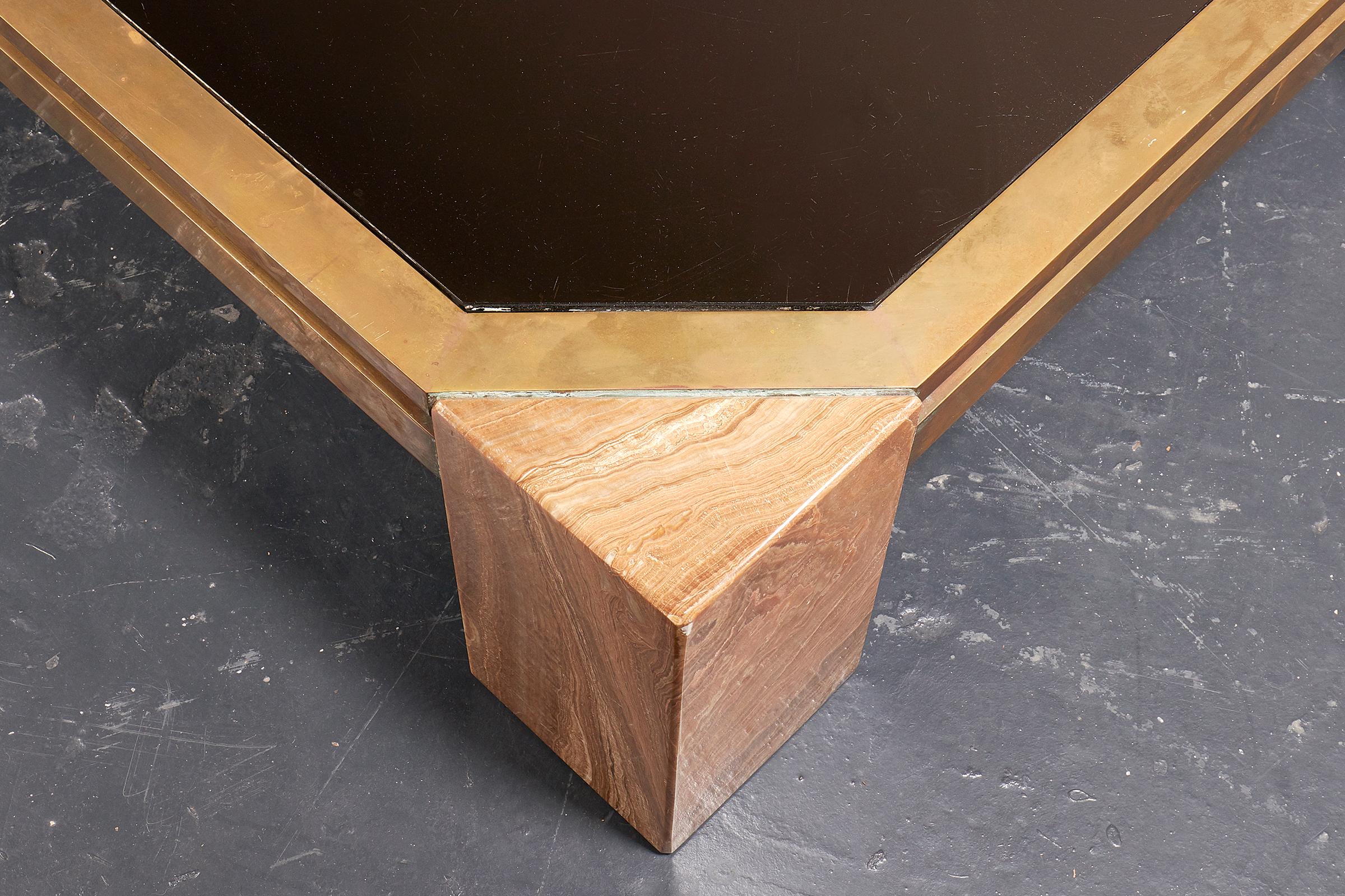 Table basse italienne en verre fumé et onyx, vers 1970, de forme rectangulaire, le verre octogonal enchâssé dans un cadre en laiton doré, pieds d'angle à section triangulaire en onyx.