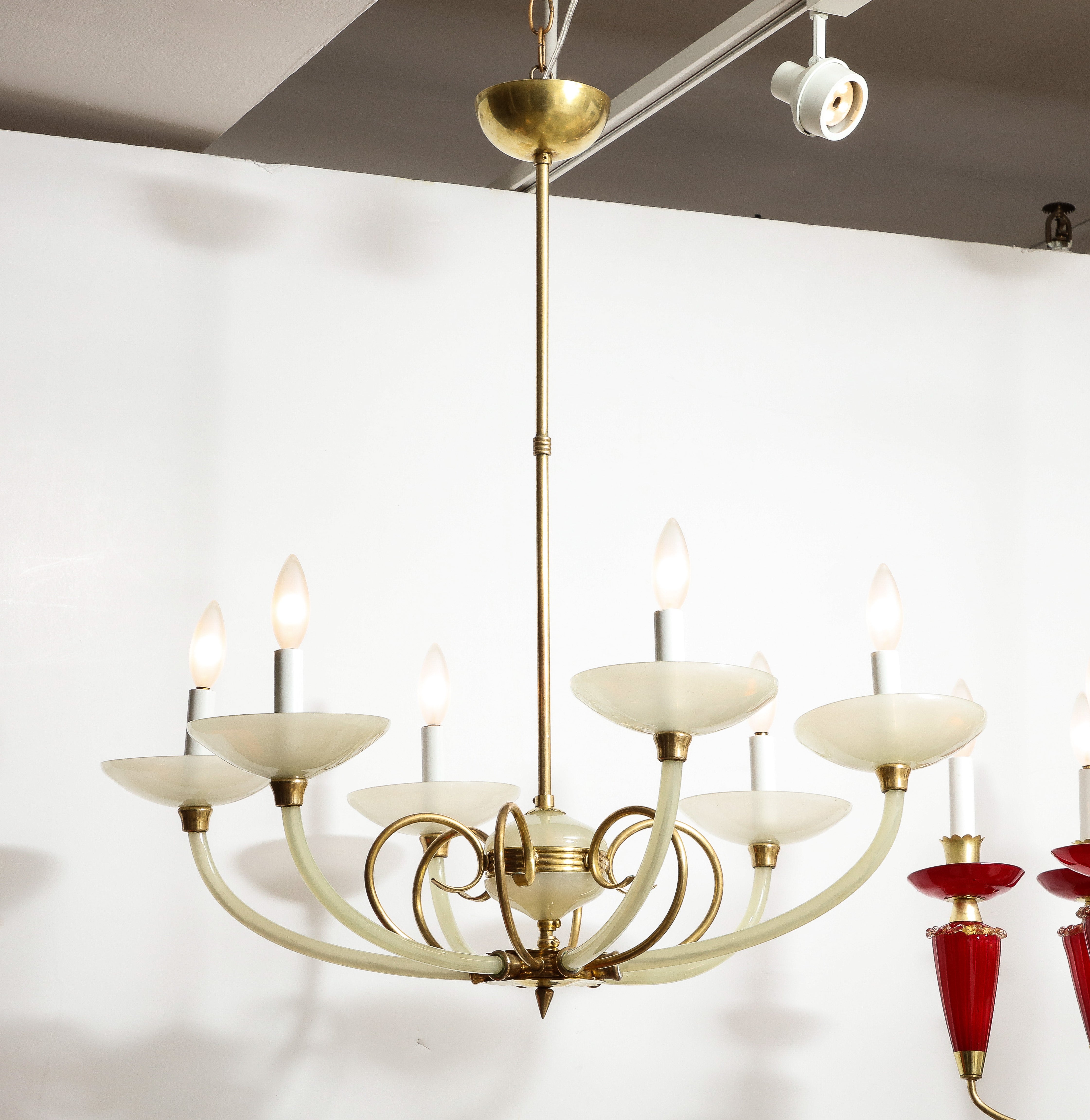 An elegant Italian opaline glass and brass six-arm chandelier. The central opaline glass ball with brass decorative banding supports six brass scrolls which attach to a finial and which emanate the six glass upturned arms with bobeche; with original