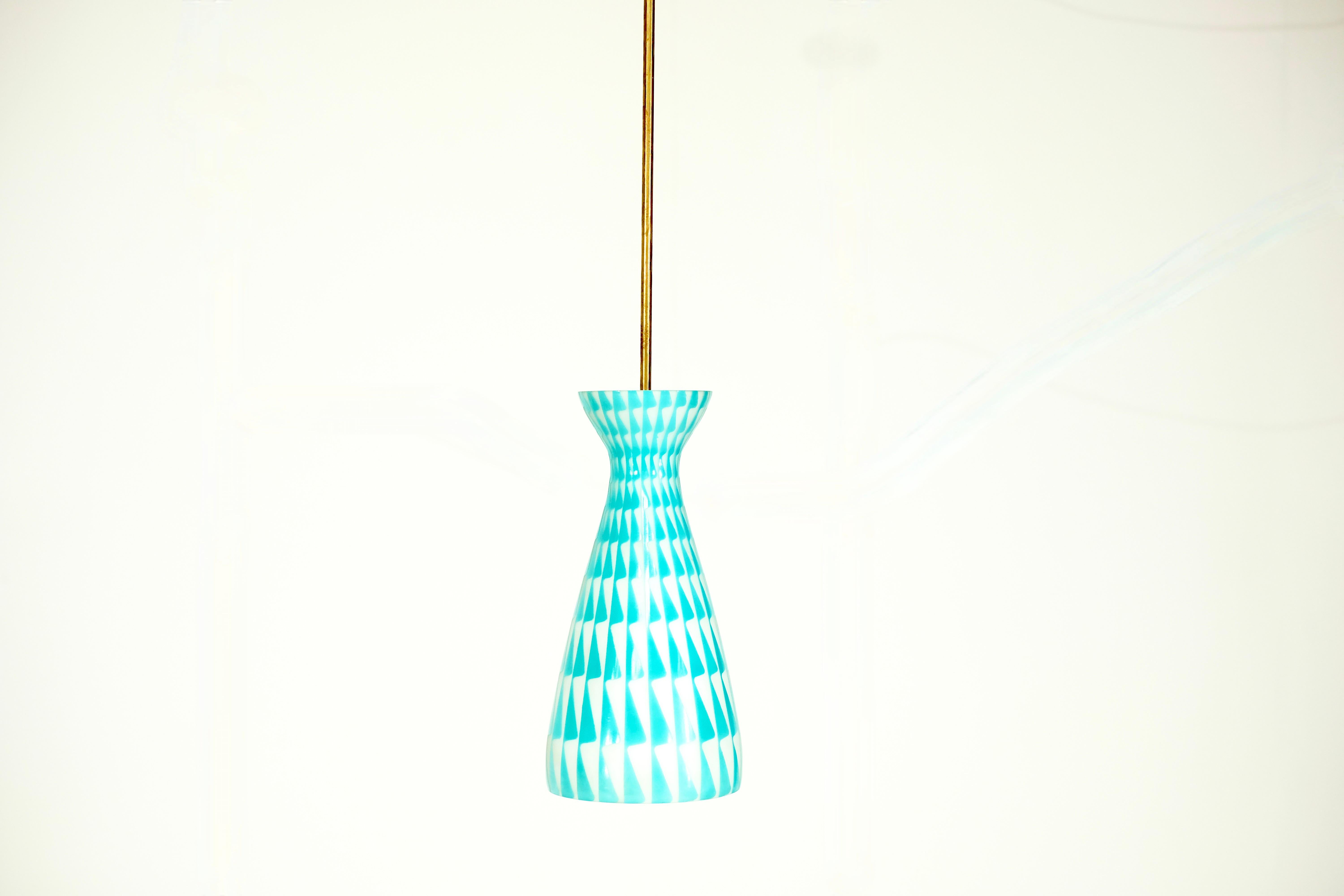 Splendida lampada a sospensione italiana in opalino con motivi bianchi e turchesi degli anni Settanta. 
Ha un'asta rigida in metallo dorato che nasconde il cavo.
L'altezza totale di questa lampada a sospensione è di 103 cm. 

È in ottime condizioni