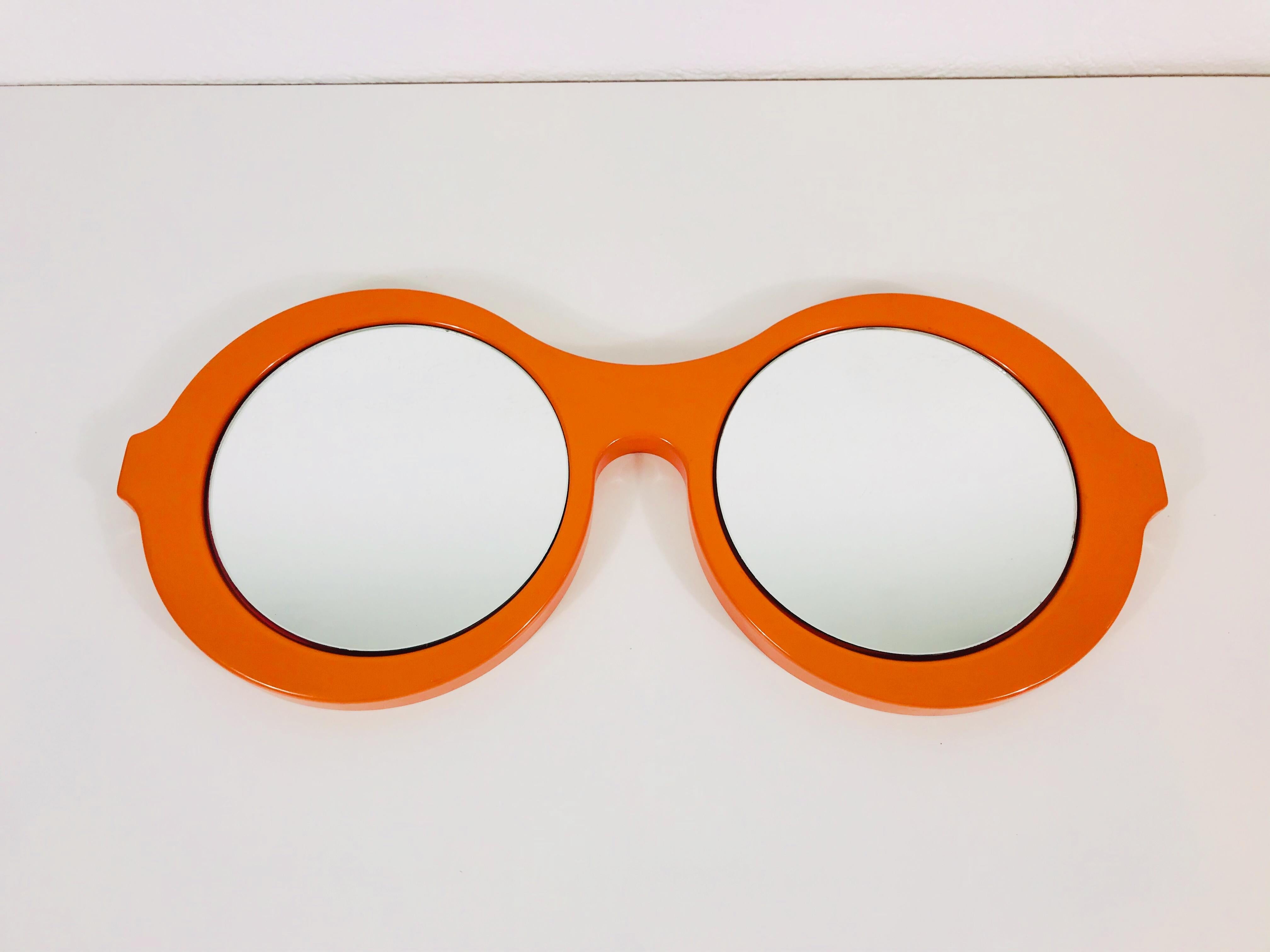 A plastic Italian hanging wall mirror. 2 glass parts. Plastic orange frame. Beautiful with its amazing design.

  