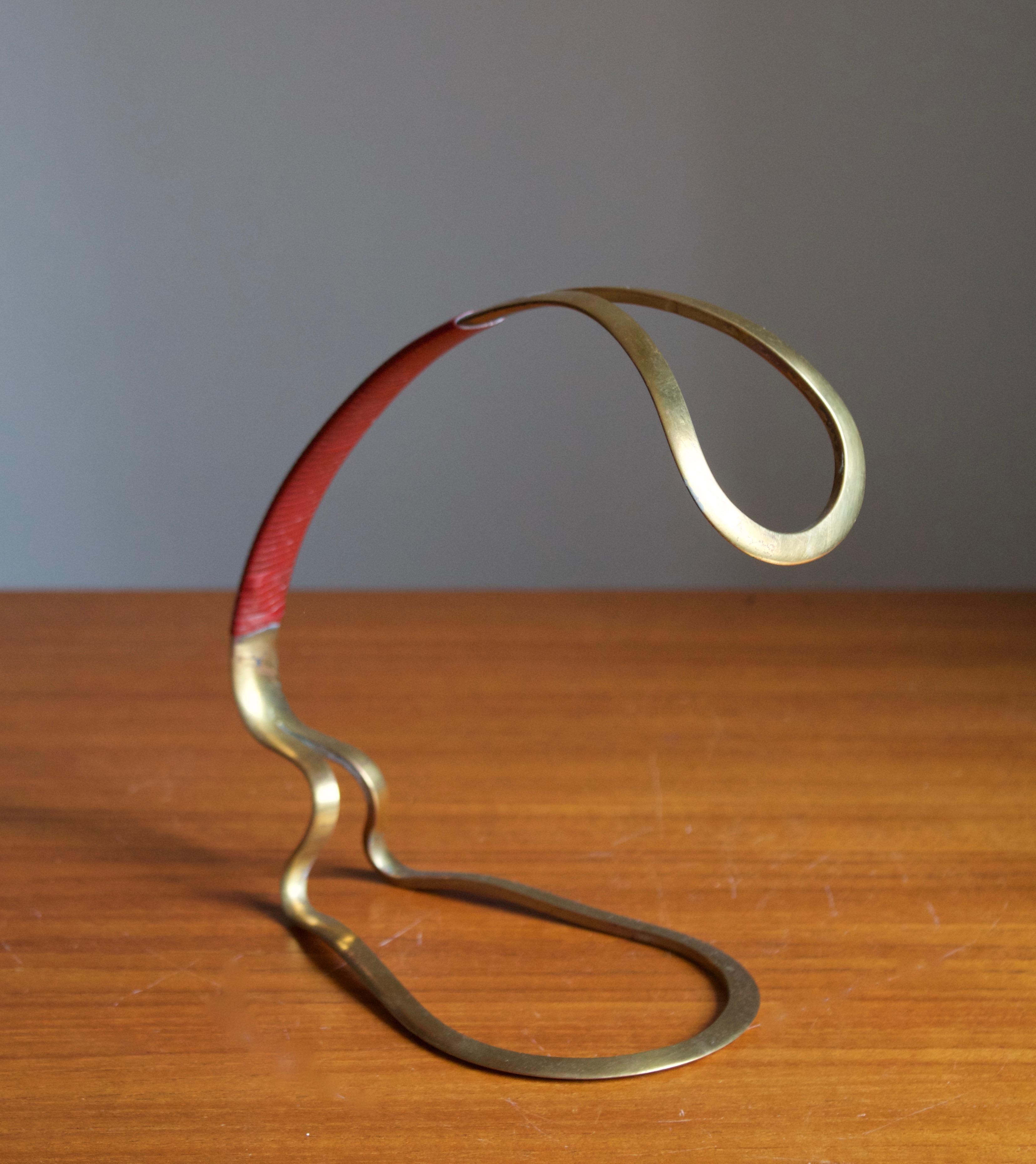 A wine bottle holder, designed and produced in Italy, 1950s.

In brass and with braided leatherette handle.