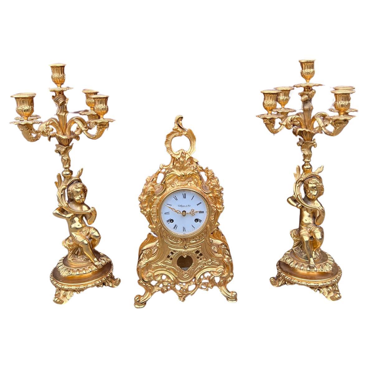 Pendule de cheminée italienne ornée avec deux candélabres figuratifs de chérubins - Ensemble de garnitures