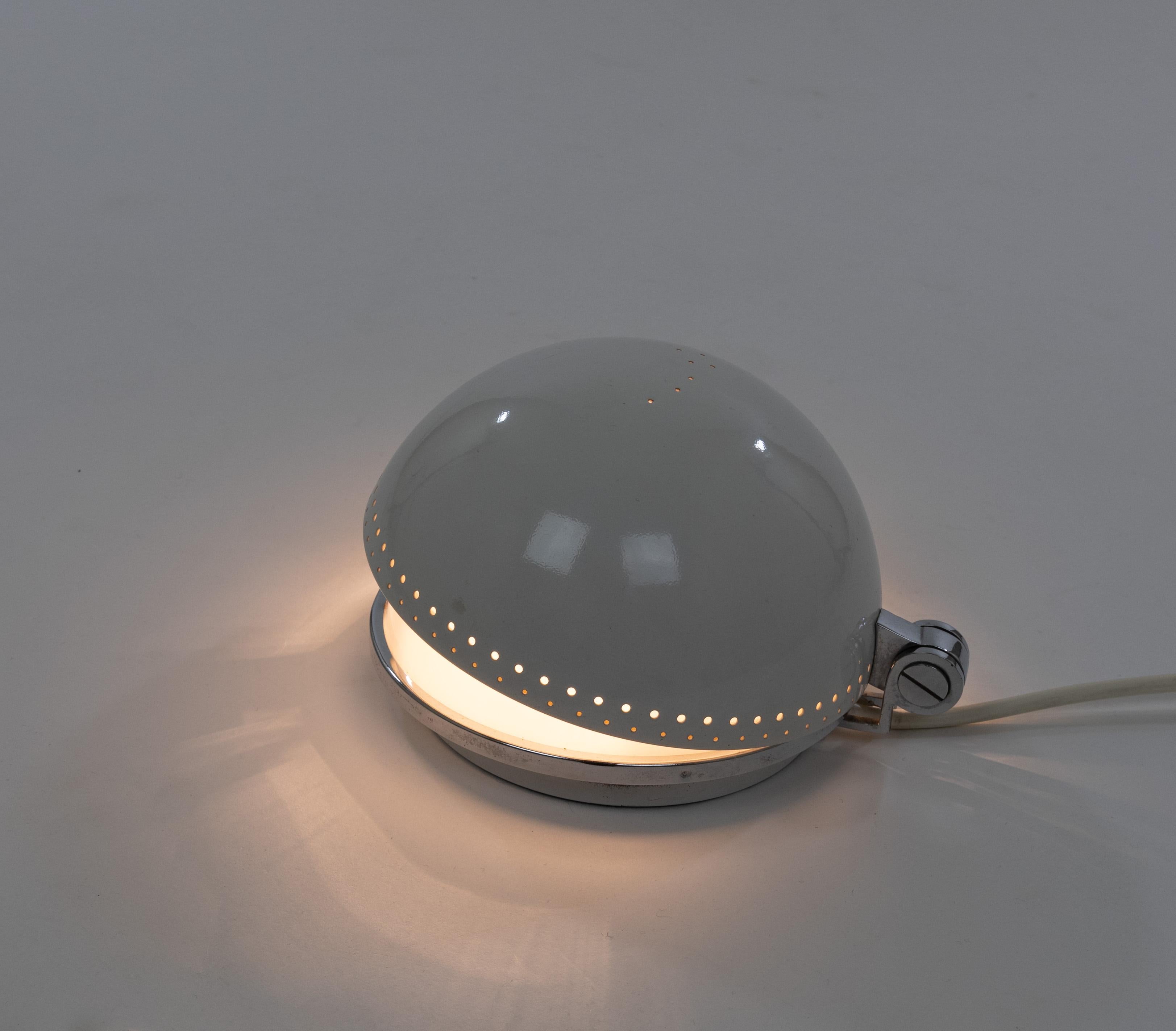 Orsa Minore table lamp made in Italy in the 1970s, possibly by Stilux.

The lamp has an ivory metal shade in which a pattern of perforated small holes playfully form the Little Bear constellation. Directly below the shade sits a half-sphere of opal
