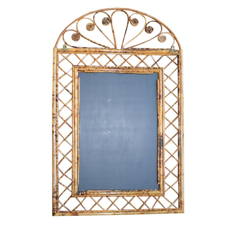 An Italian scrolled burnt bamboo and rattan wall mirror in the style of Franco Albini. The piece is rectangular in shape and created with a rattan and bamboo frame which surrounds the glass. The edges of the mirror are decorated with bamboo
