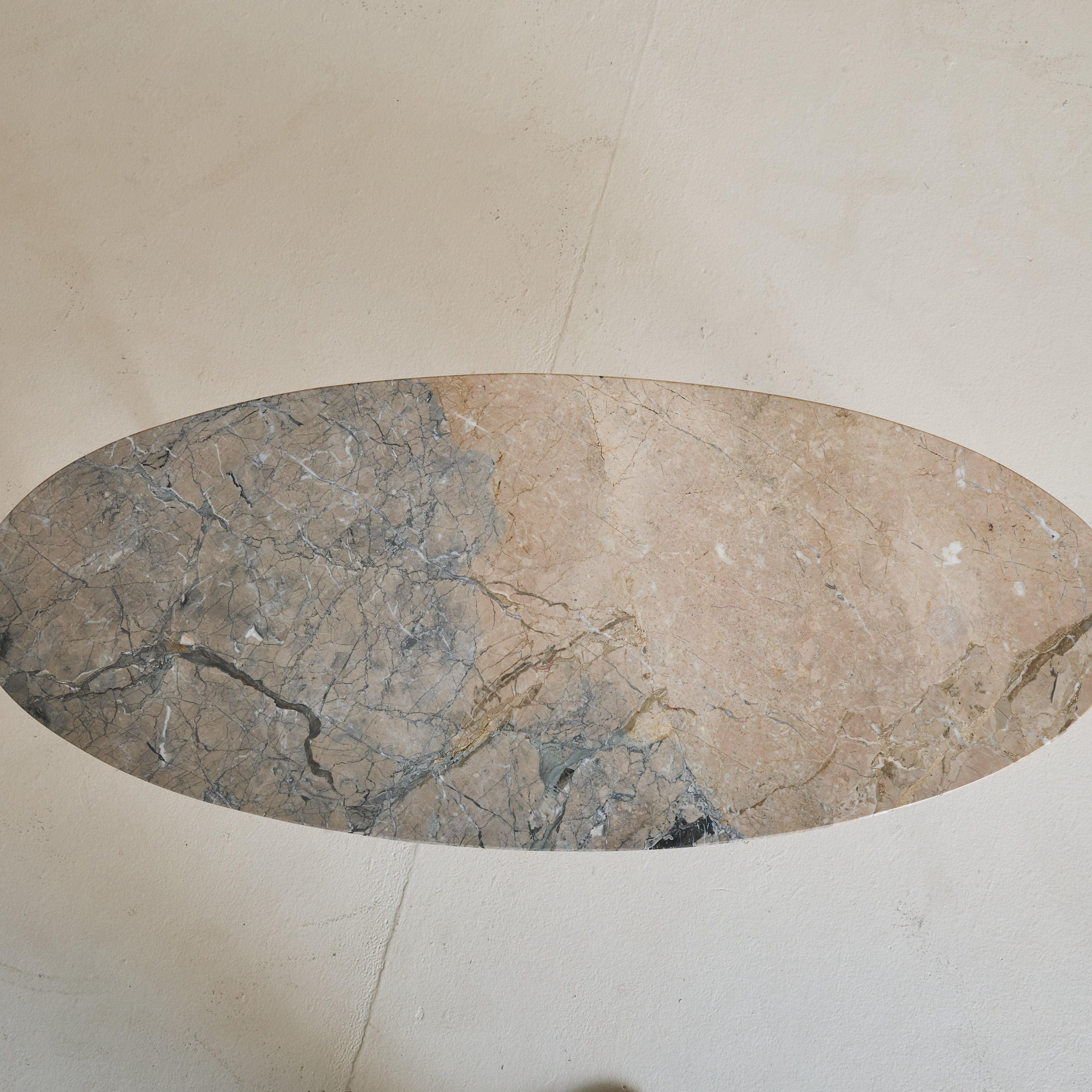 Table basse ovale italienne des années 1950 avec un plateau en marbre bicolore. La pierre naturelle, avec ses veines complexes, met en valeur un jeu organique de teintes chaudes beiges et froides grises. Cette table est soutenue par des pieds en