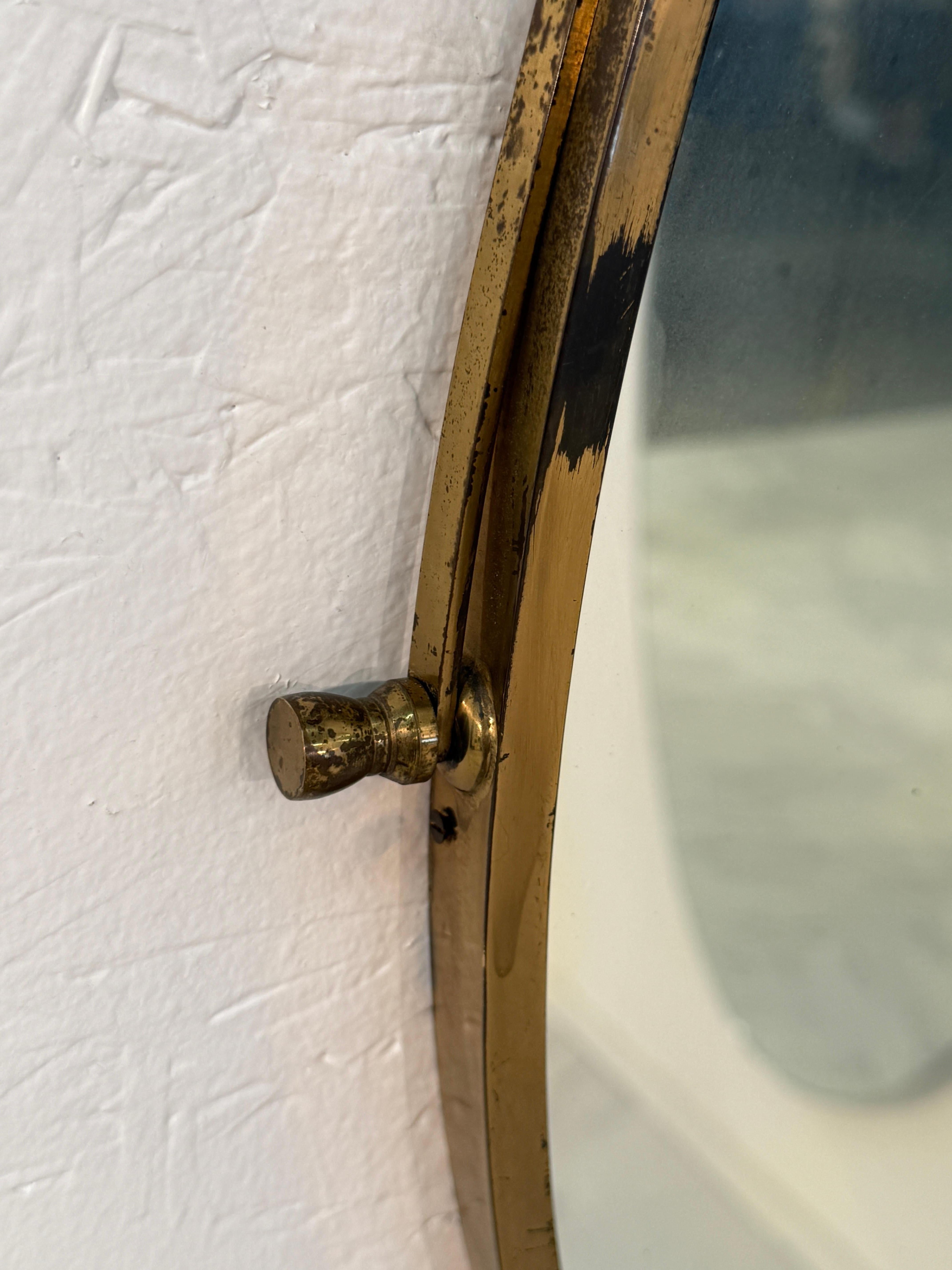 Italiano Italian oval mirror from the 1950s, featuring a brass frame suspended by a twist in vendita