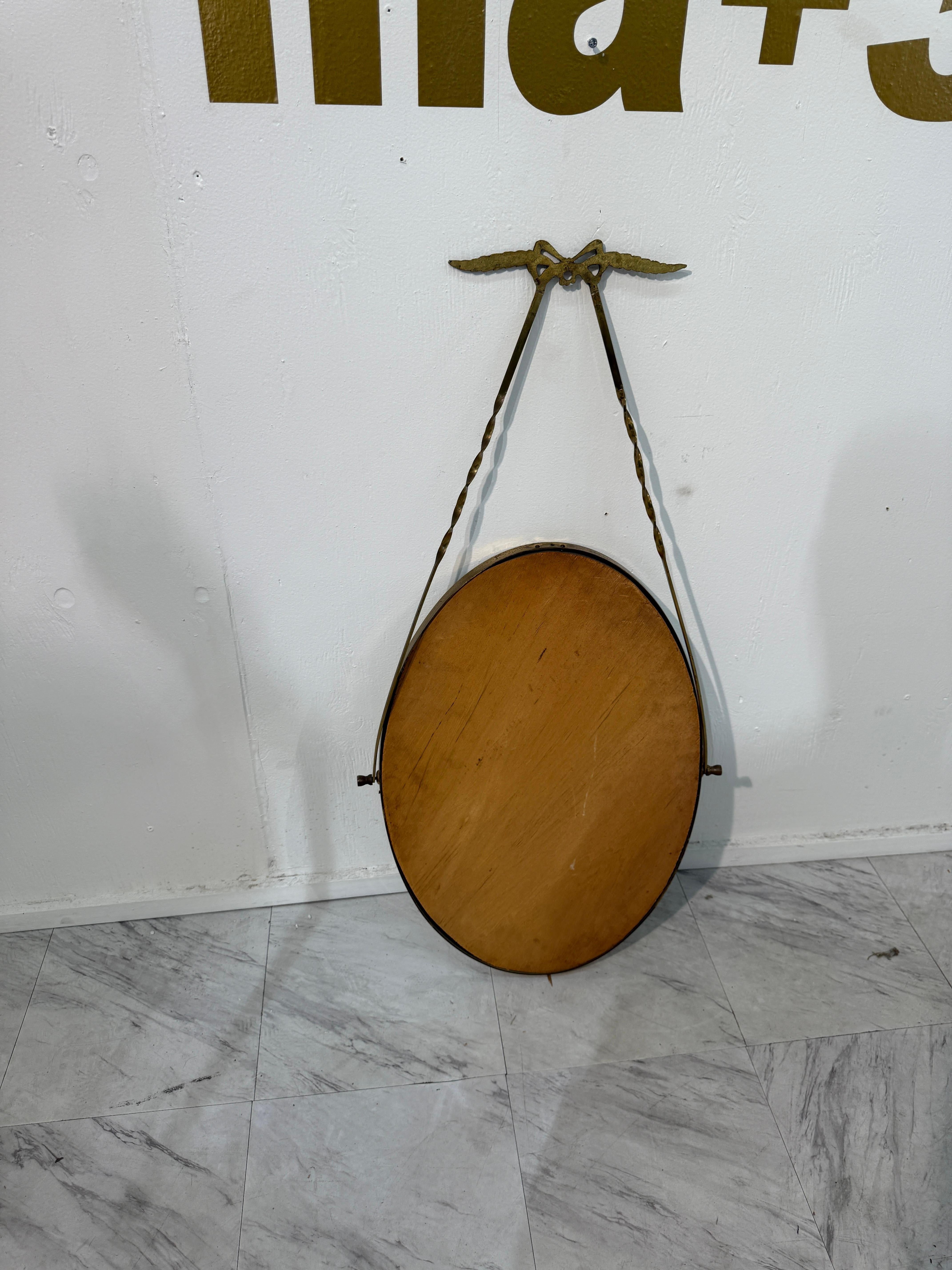 Italian oval mirror from the 1950s, featuring a brass frame suspended by a twist in vendita 1