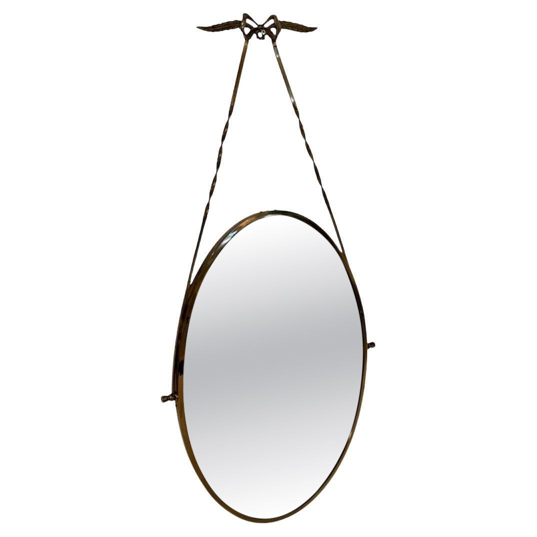Italian oval mirror from the 1950s, featuring a brass frame suspended by a twist