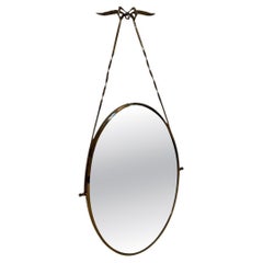 Italian oval mirror from the 1950s, featuring a brass frame suspended by a twist