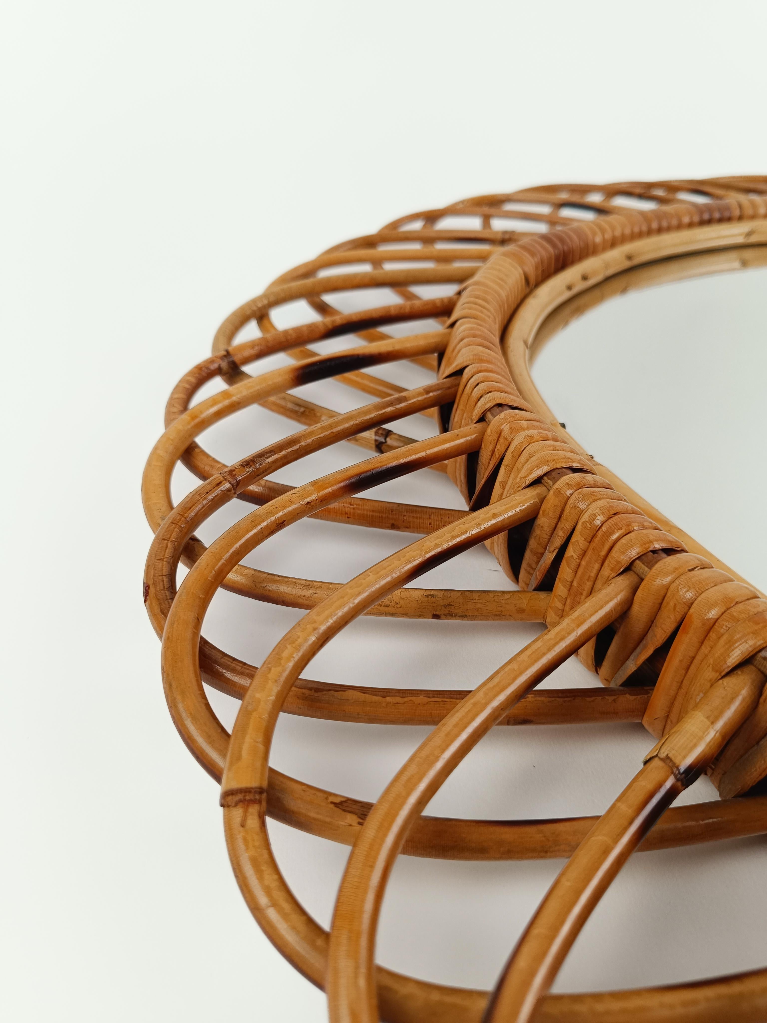 Splendid oval mirror made in Italy between the 60s and 70s
This vintage mirror has an airy and light sunburst structure obtained by the hand bending of thin rattan canes that create large petals around the oval frame.
The mirror is in original good