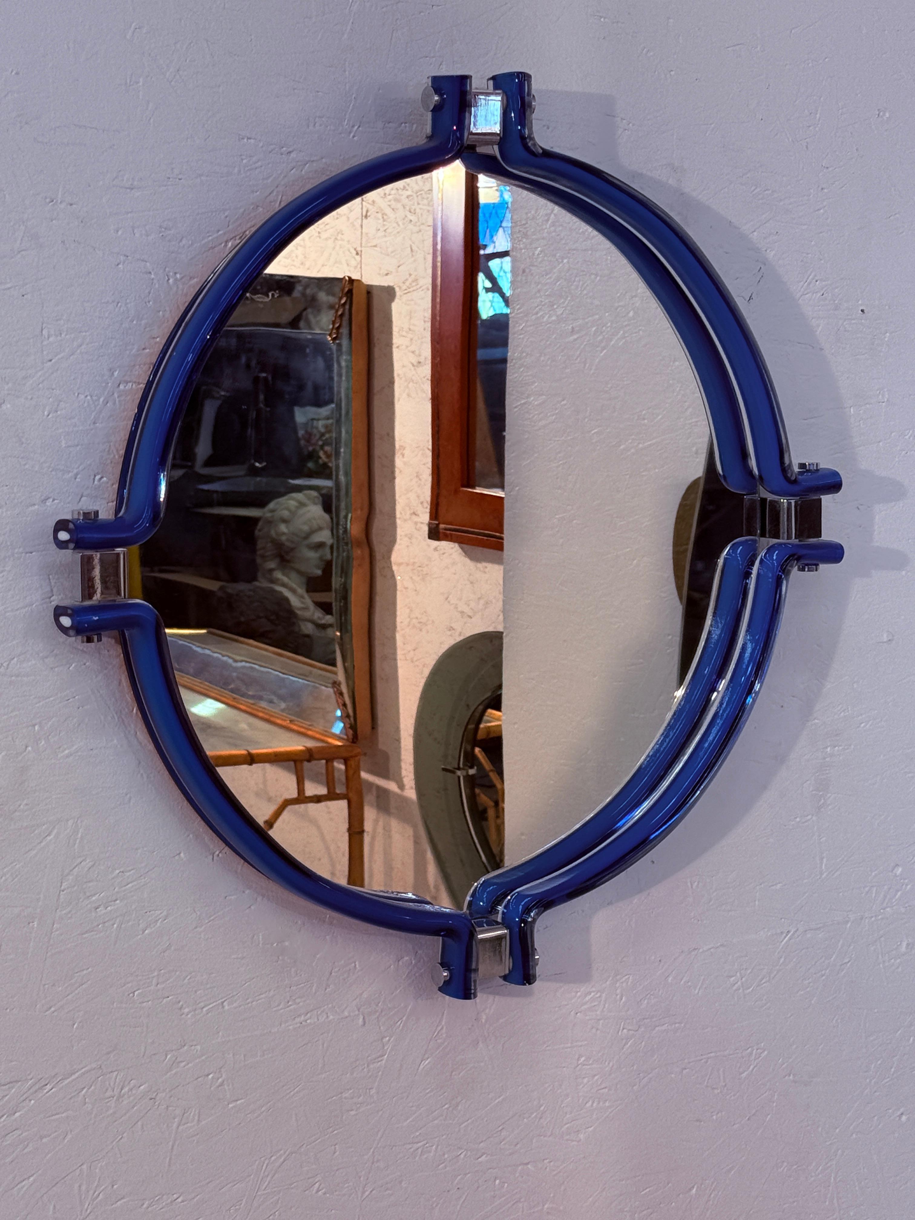 Miroir mural italien des années 80 se distinguant par sa forme ovale et son cadre sculptural audacieux.

Le miroir est entouré d'une structure bleue brillante en verre avec des connecteurs chromés, ce qui lui confère une présence futuriste et