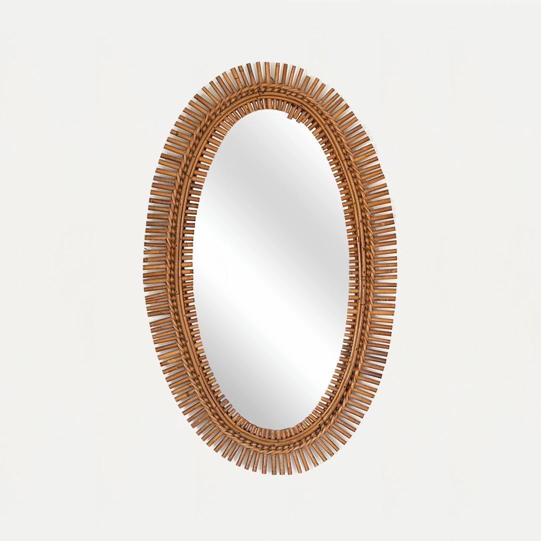 Italian rattan mirror in an oval shape with rattan encompassing the mirror. Nice vintage condition showing age and patina.