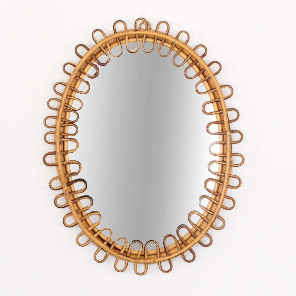 Italian rattan mirror in an oval shape with looping rattan encompassing the mirror. Nice vintage condition with original finish and mirror. Perfect for powder room. Matching pair available. 