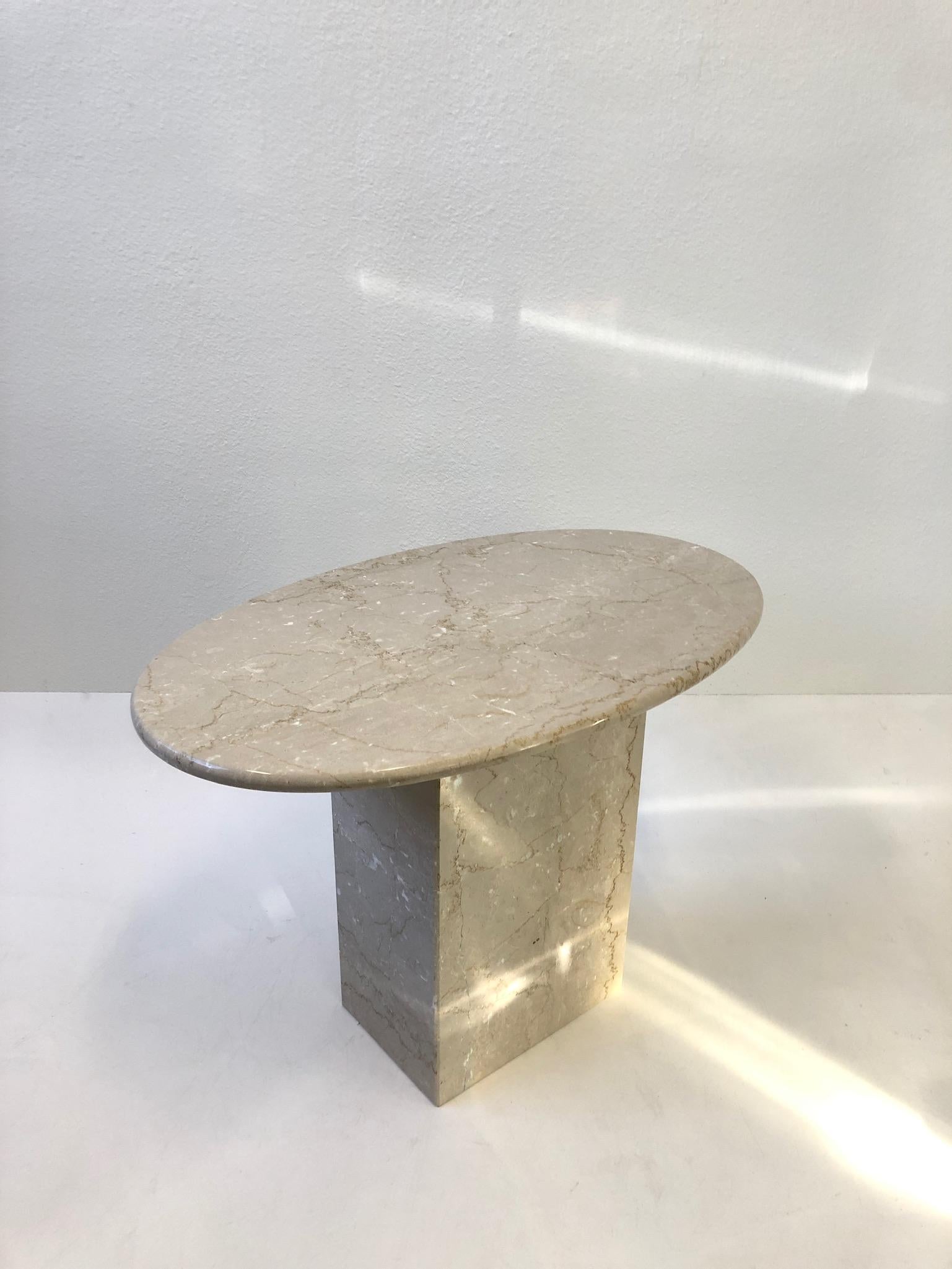 A beautiful 1970s Italian oval travertine side table. 
The tables oval top just sits on the rectangular base. 
Newly professionally polished. 
Measurements: 18.25” deep, 19.75” wide and 21” high.
