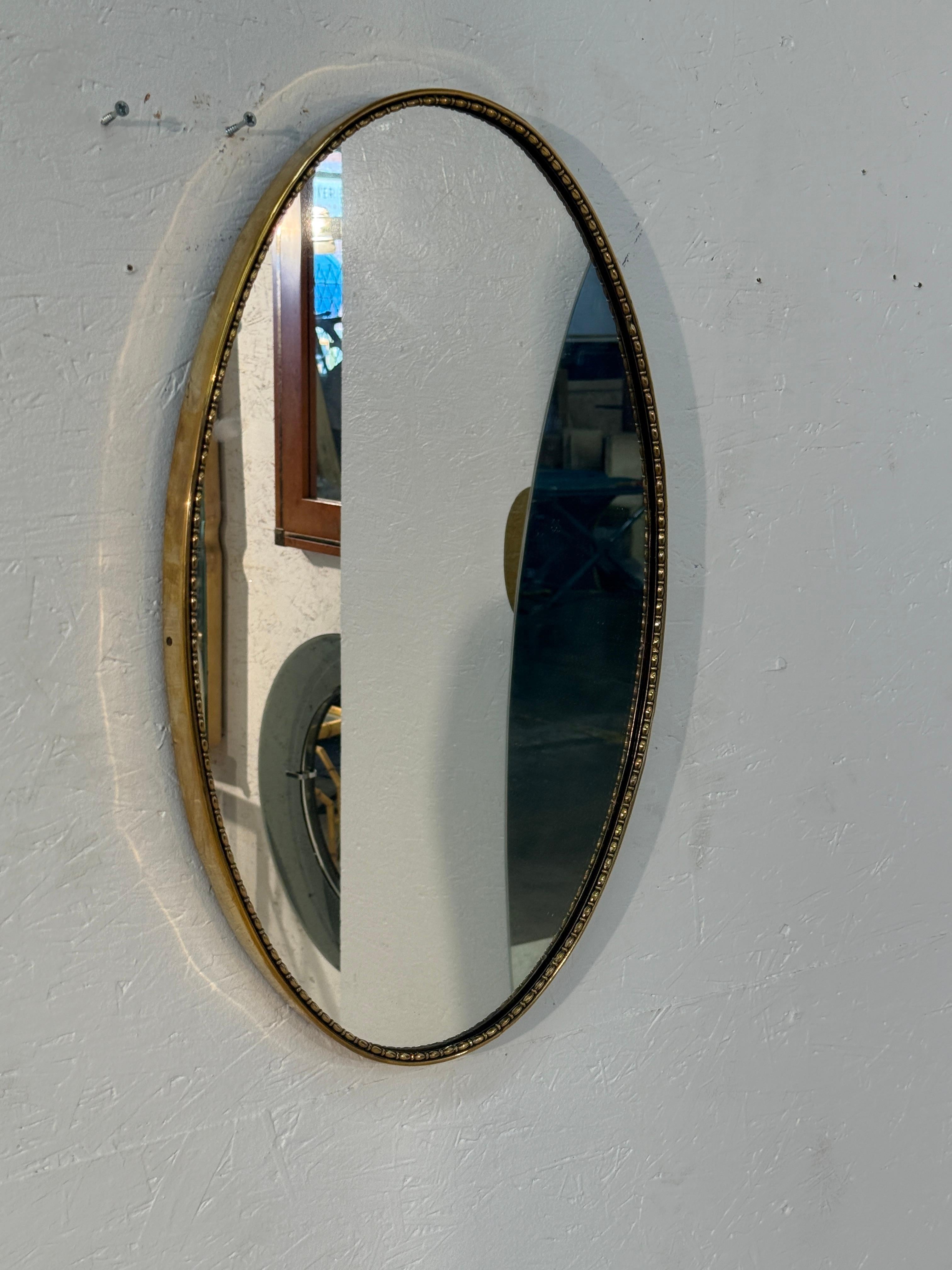 Miroir mural italien ovale et raffiné, encadré de laiton avec une délicate bordure perlée. Sa forme allongée et ses détails décoratifs subtils reflètent l'artisanat italien du milieu du siècle, offrant à la fois élégance et simplicité intemporelle.