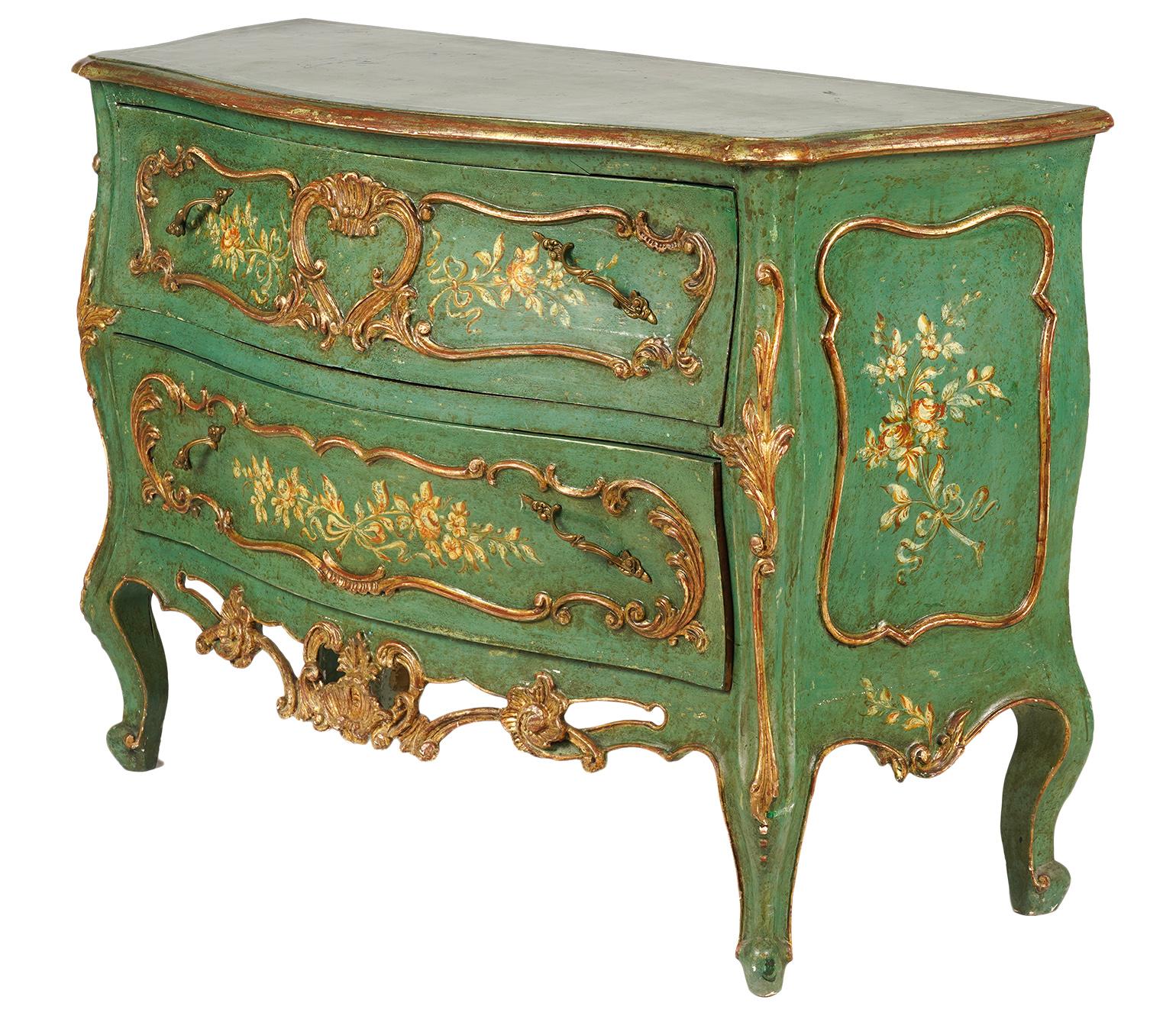 This charming Italian paint and parcel gilt serpentine front rococo style two drawer commode, dating to the mid 20th century, features a shaped top above two long drawers. The drawer fronts and the sides of the commode are decorated with carved