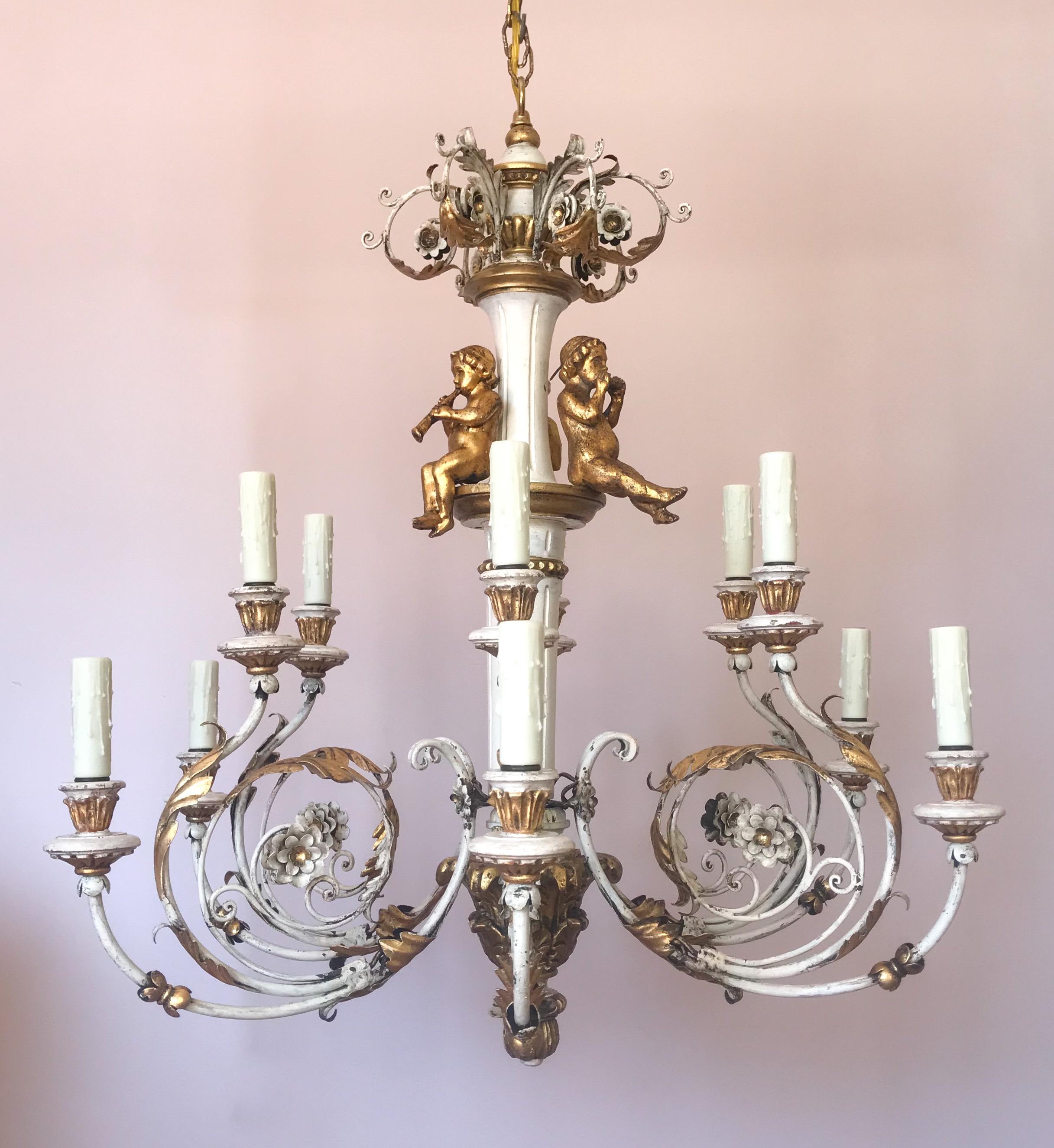 Gorgeous, 1940s Italian painted and parcel-gilt carved wood two-tier, twelve-light chandelier in the Louis XVI style. 

This beautiful chandelier consists of a painted carved wood column with 3 gilded wood cherubs playing musical instruments. Six