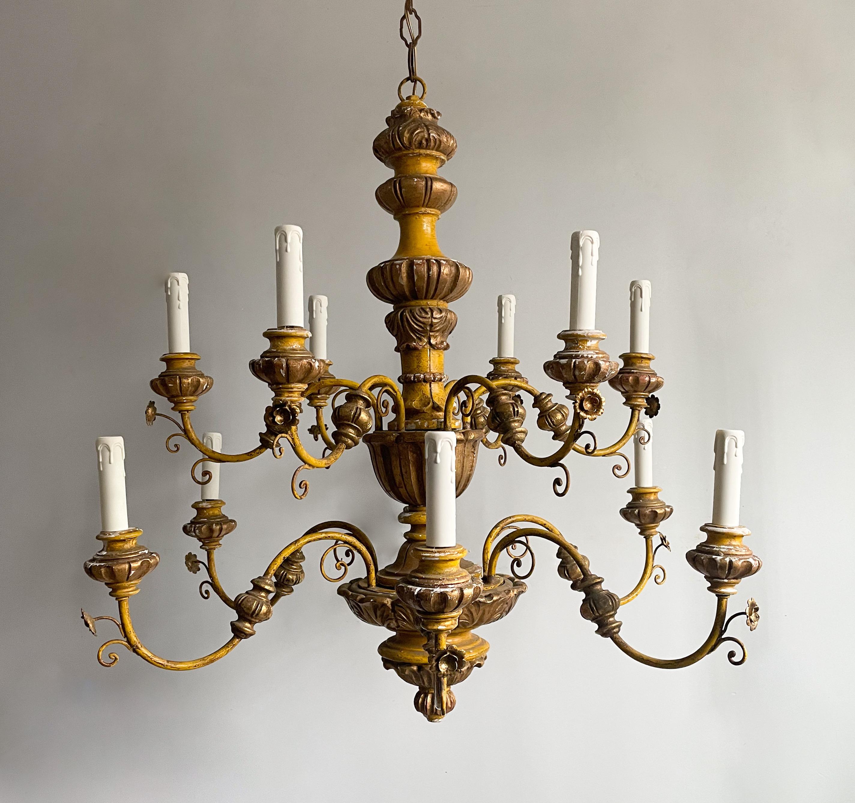 Gorgeous, Italian 1950s painted and parcel-gilt chandelier imported by Feldman Lighting, Los Angeles.

The chandelier consists of a two-tier wrought iron and carved wood frame painted in a rich yellow finish with gilded accents.

Paint finish is