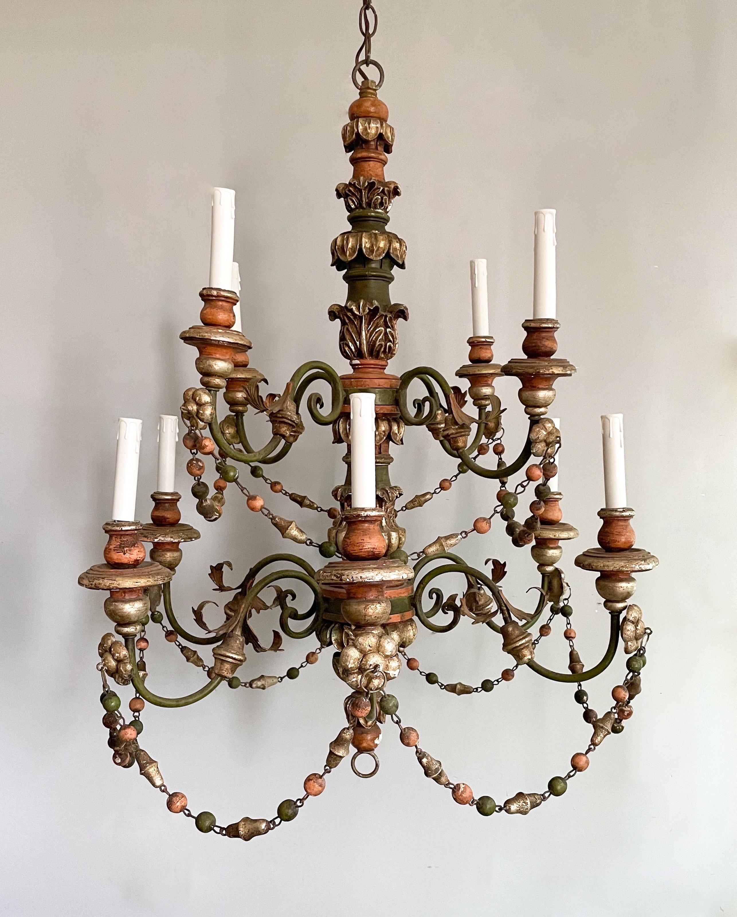 Gorgeous, vintage Italian painted and parcel-gilt carved wood and iron chandelier. 

The chandelier consists of two tiers with a total of 10 lights. 

 Antiqued green, orange and silver leafed paint finish. 

Wired and in working condition, it