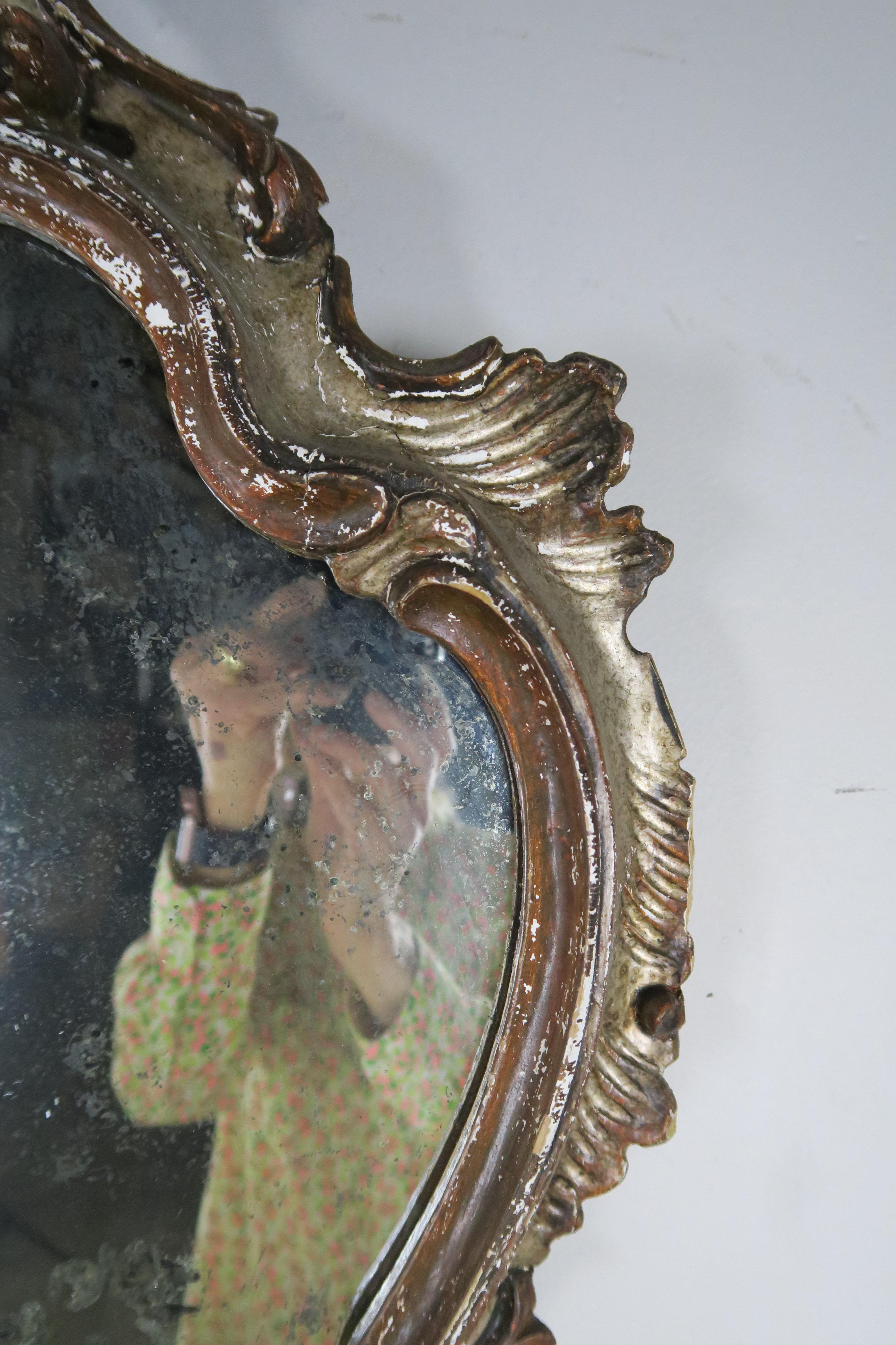 Miroir en forme de sablier de style rococo italien, sculpté dans le bois et peint à l'ancienne.