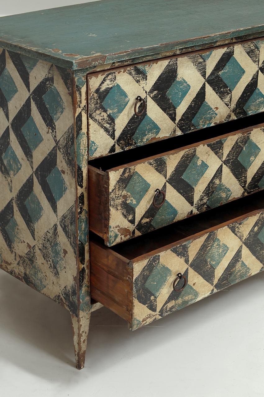 Dipinto a mano nei ricchi toni dell'avorio, del blu e del nero, questo mobile vintage italiano presenta un design geometrico senza tempo e un'elegante patina invecchiata.

Dotato di tre spaziosi cassetti e di graziose gambe affusolate, questo mobile