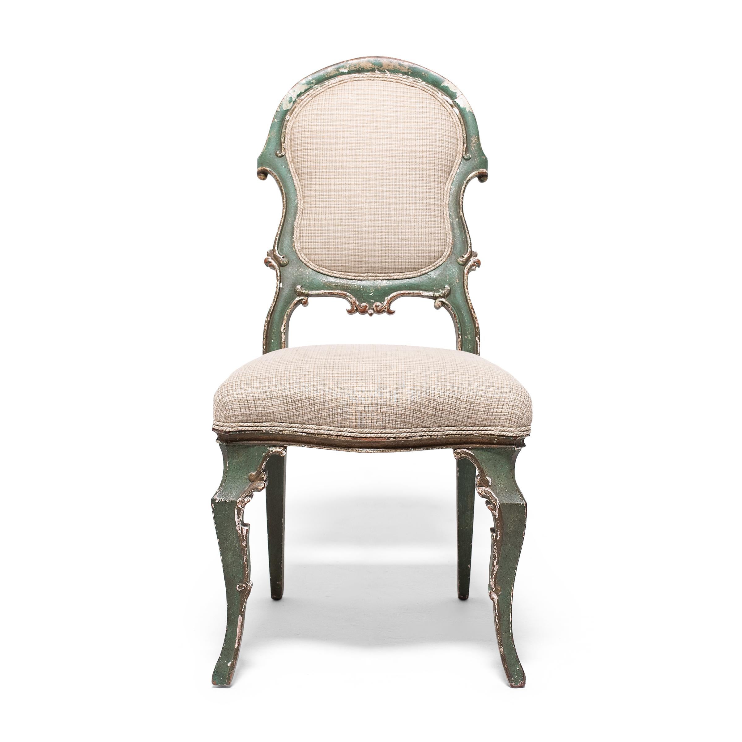This upholstered dining chair wonderfully recreates the delicate, feminine seating of 17th and 18th century European furniture, designed in the style of Venetian Rococo and Louis XV. Dated to the early 19th century, the chair has a padded seat and