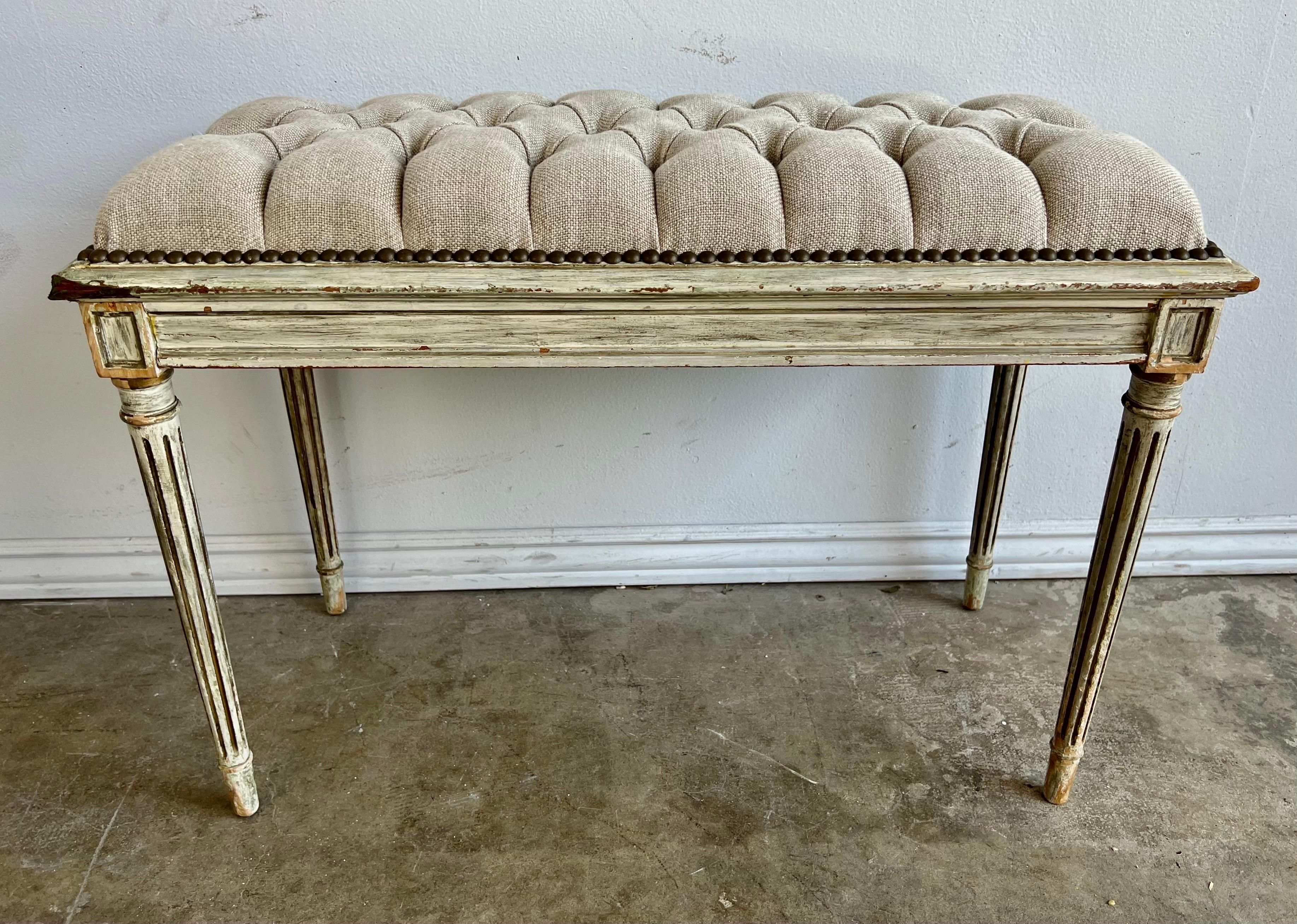 Italian Neoclassical style linen tufted upholstered bench. The bench stands on four straight fluted legs known as 