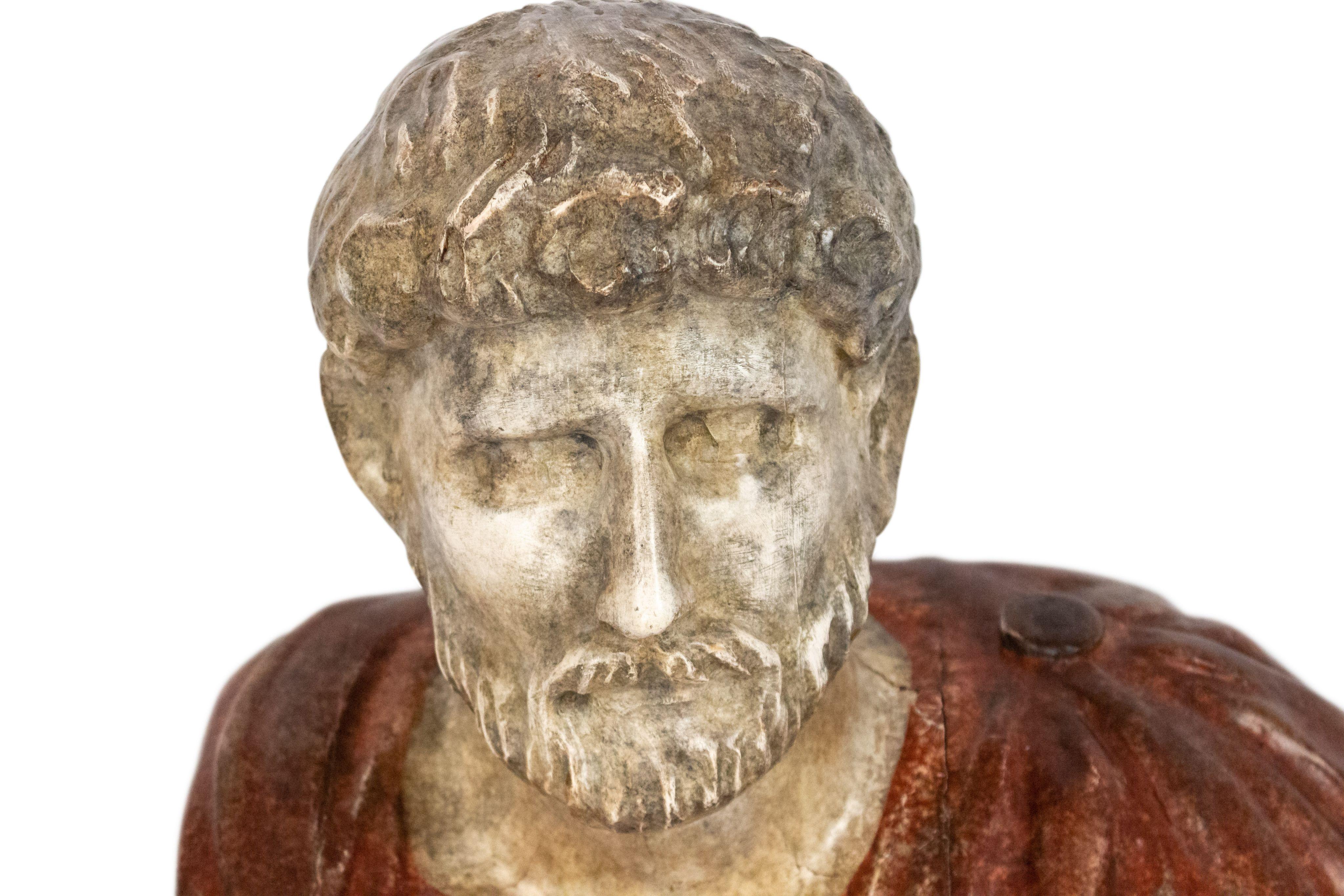 Busto de composición de estilo neoclásico italiano (s. XIX/XX), pintado de imitación, de un emperador romano vestido con una toga roja y montado sobre una base cuadrada negra.
  