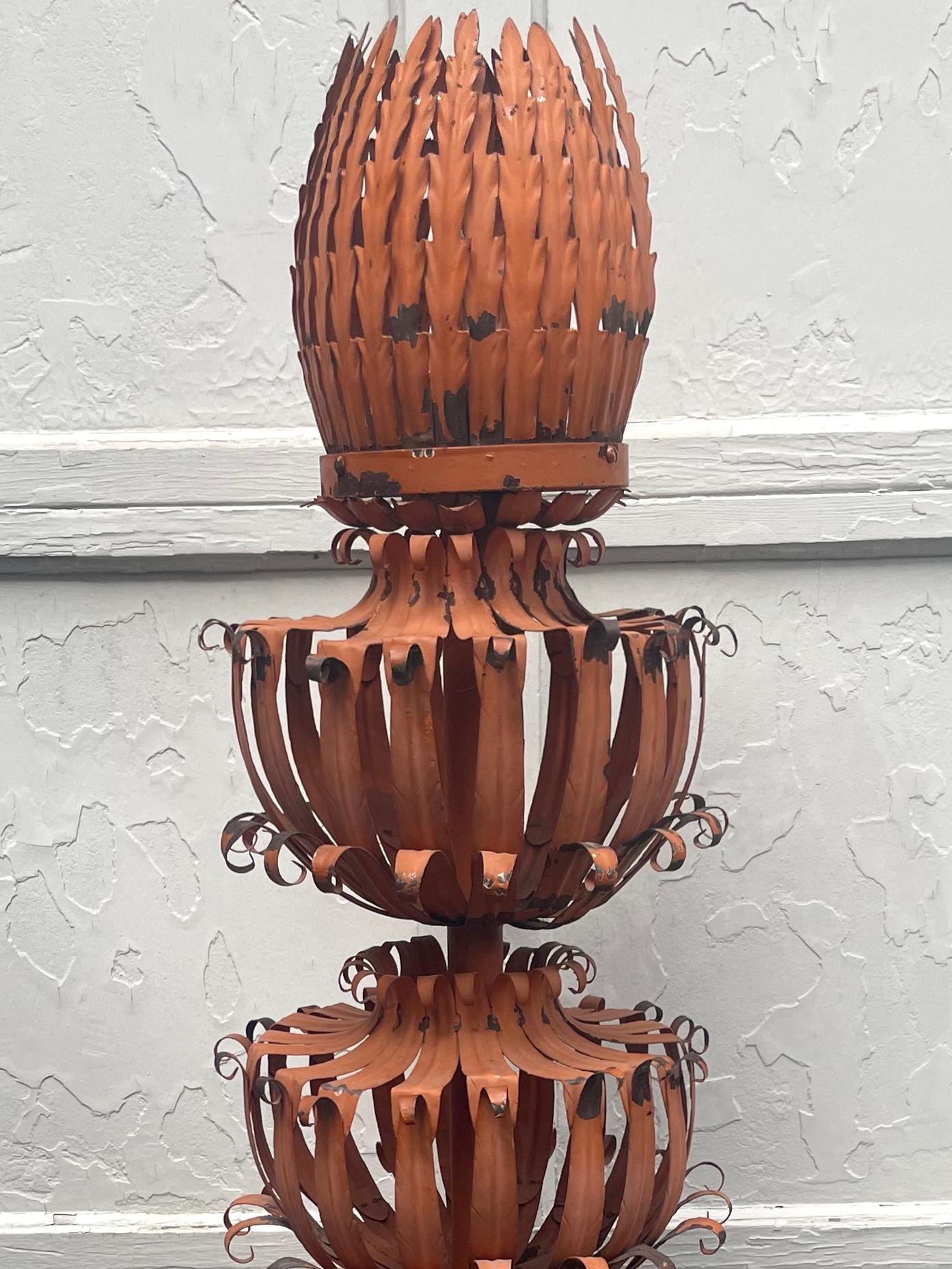 Italian painted tole torchiere. Fantastical botanical inspired six tier open basket work burnt orange painted tole torchiere sprouting large artichoke form finial enclosing electrical bulb which when illuminated cast a beautiful reflective pattern.
