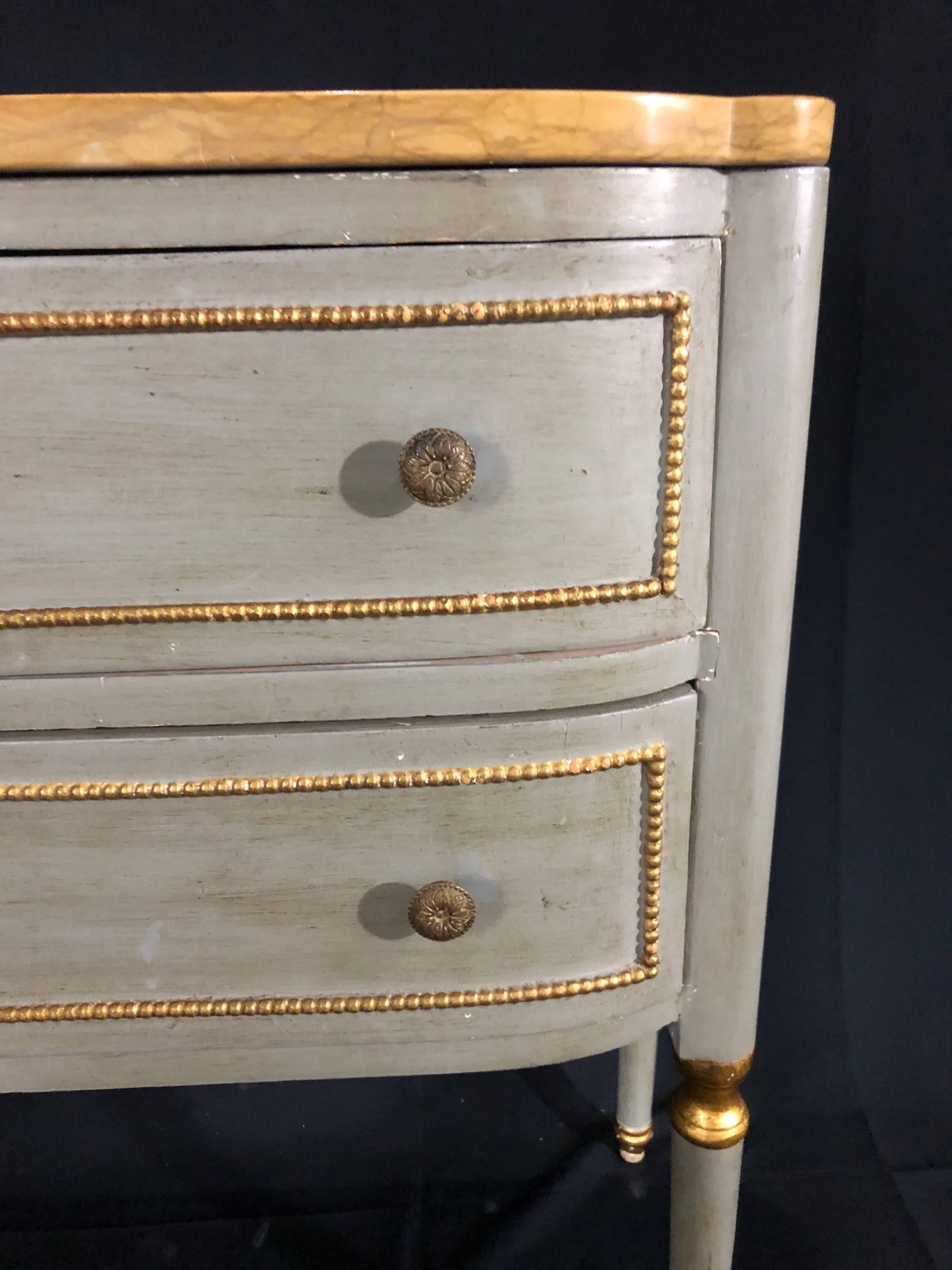 Italian painted 2 drawer commode with gold marble top over beautiful Gustavian style subtle blue painted body with gold gilt accents. Two drawers make up the front with stunning beaded gold gilt trim. The discreet rectangular painted surround and