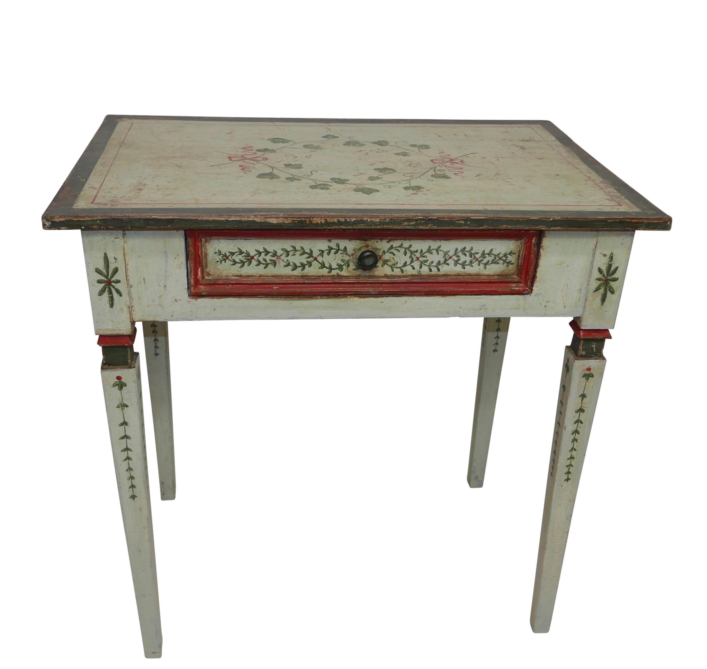 A pale green painted writing table, the top painted with ribbon tied Ivy vines above an apron painted with intertwined strands of leaves and red berries, having a single center drawer and standing on square tapering legs,
Northern Italian, circa