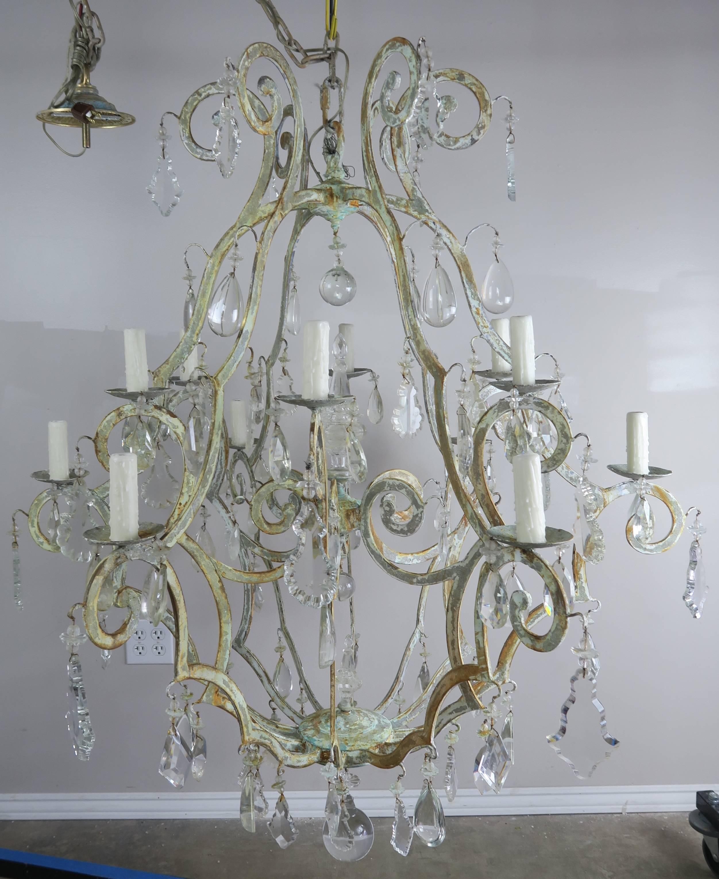Italian wrought iron twelve-light chandelier with a beautiful soft painted finish depicting shades of worn paint from years of use. The fixture has been newly rewired with drip wax candle covers. It includes chain and canopy and is ready to install.