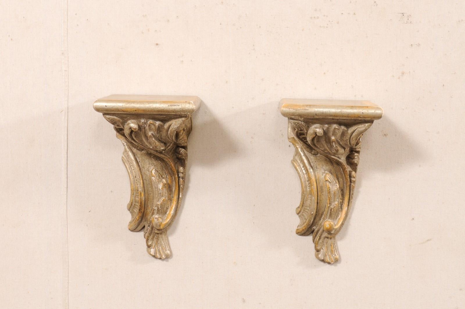 An Italian pair of carved-wood hanging wall brackets from the 19th century. These antique architectural wall decorations from Italy each feature a nearly-square flattened top shelf, above an elegantly three-dimensionally carved rinceau motif below.