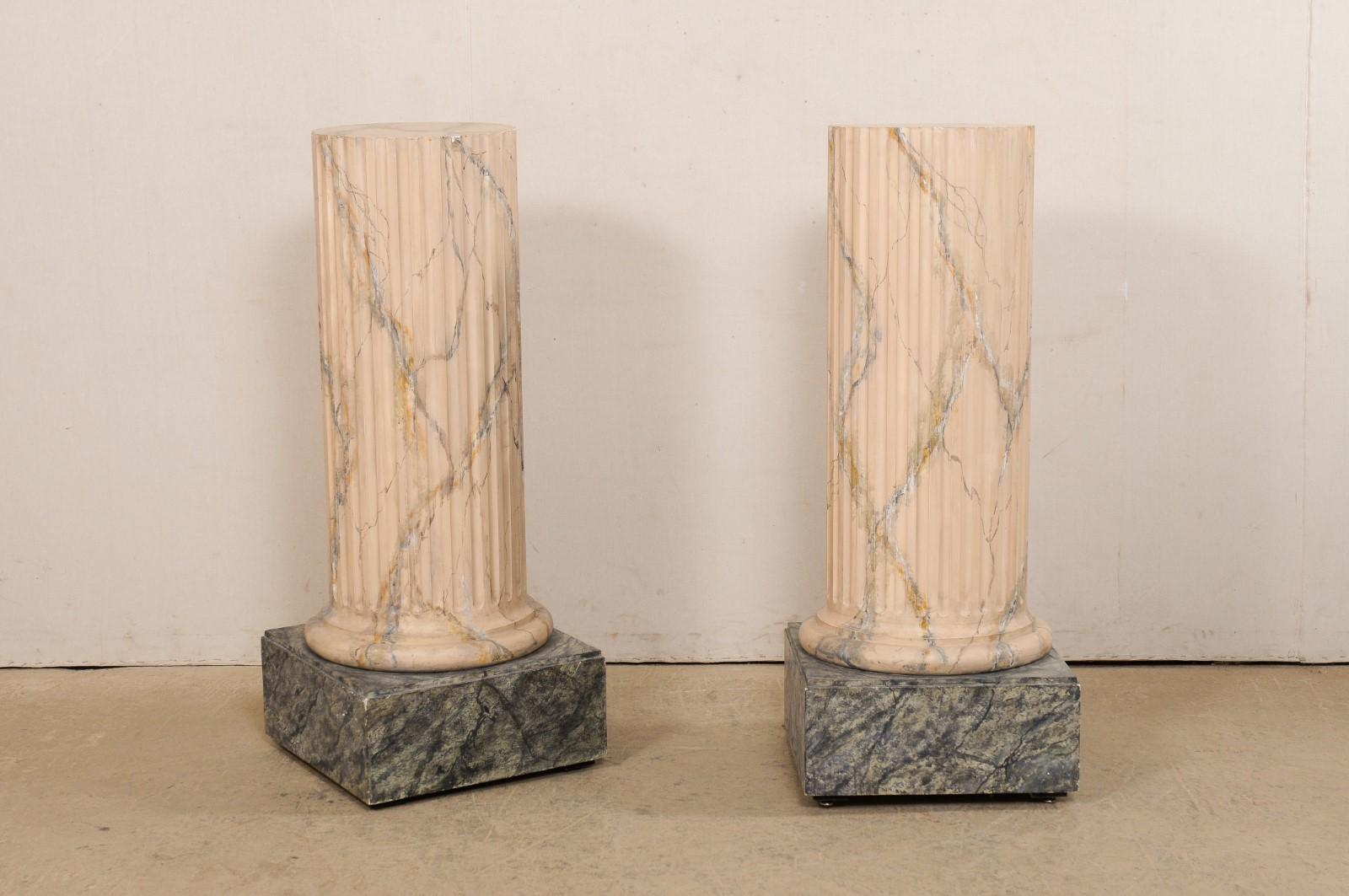 An Italian pair of carved-wood fluted column pedestals, with their original faux marble painted finish, from the mid 20th century. This pair of pedestals are circular-shaped, with flat tops measuring 15.25