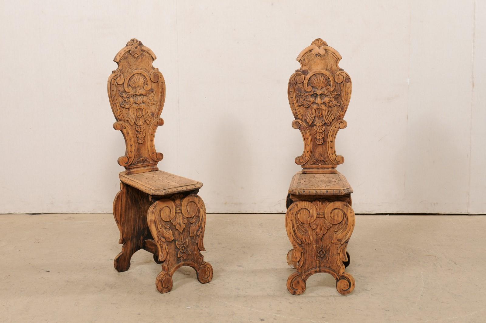 An Italian pair of Renaissance style Sgabelli chairs from the turn of the 19th and 20th century. This pair of antique wood chairs from Italy, (often referred to as a Sgabello chair; an elaborately carved hall chair intended primarily for decorative