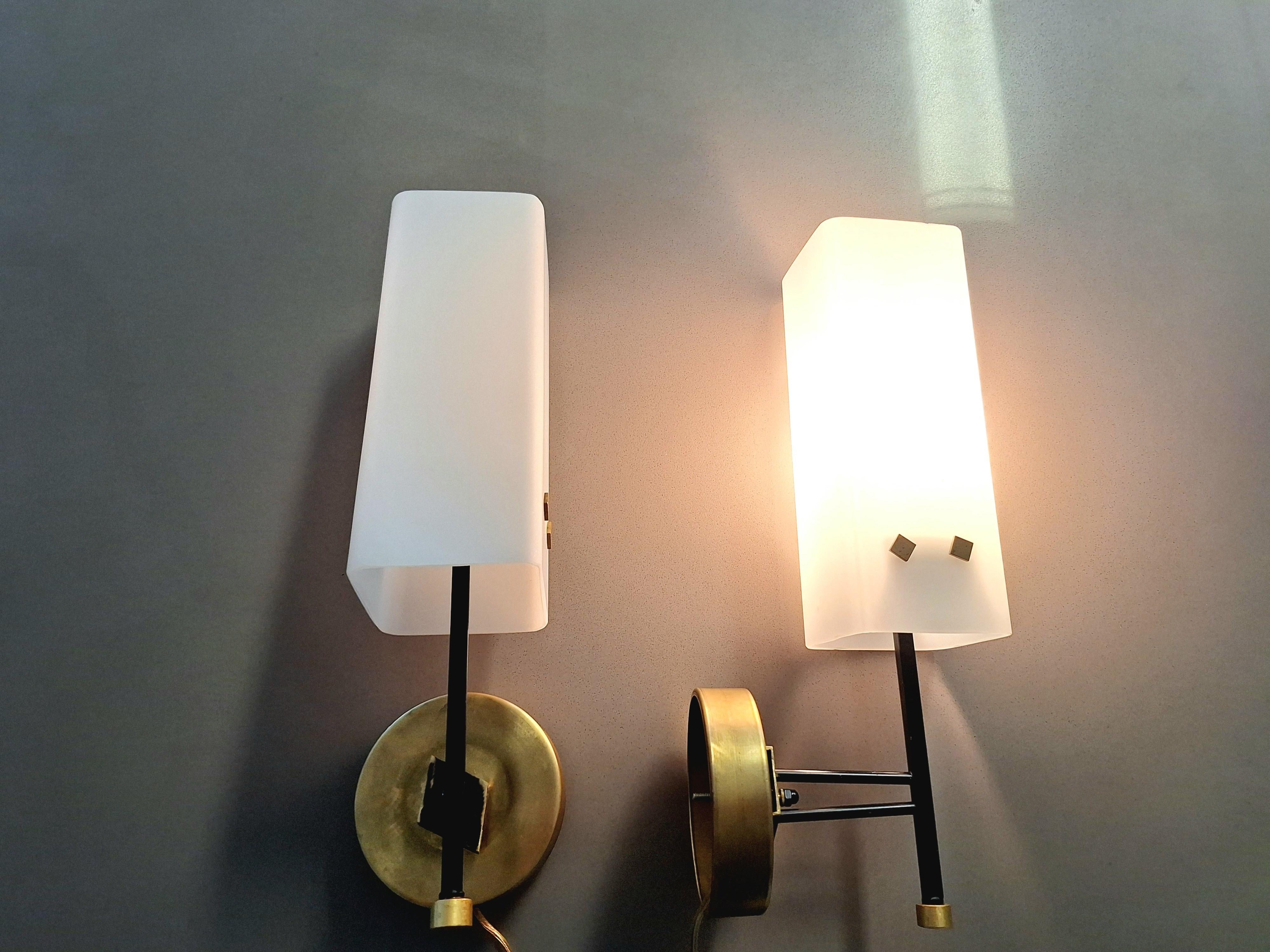 Coppia di lampade da parete italiane. Struttura in ottone e vetro opalino bianco.