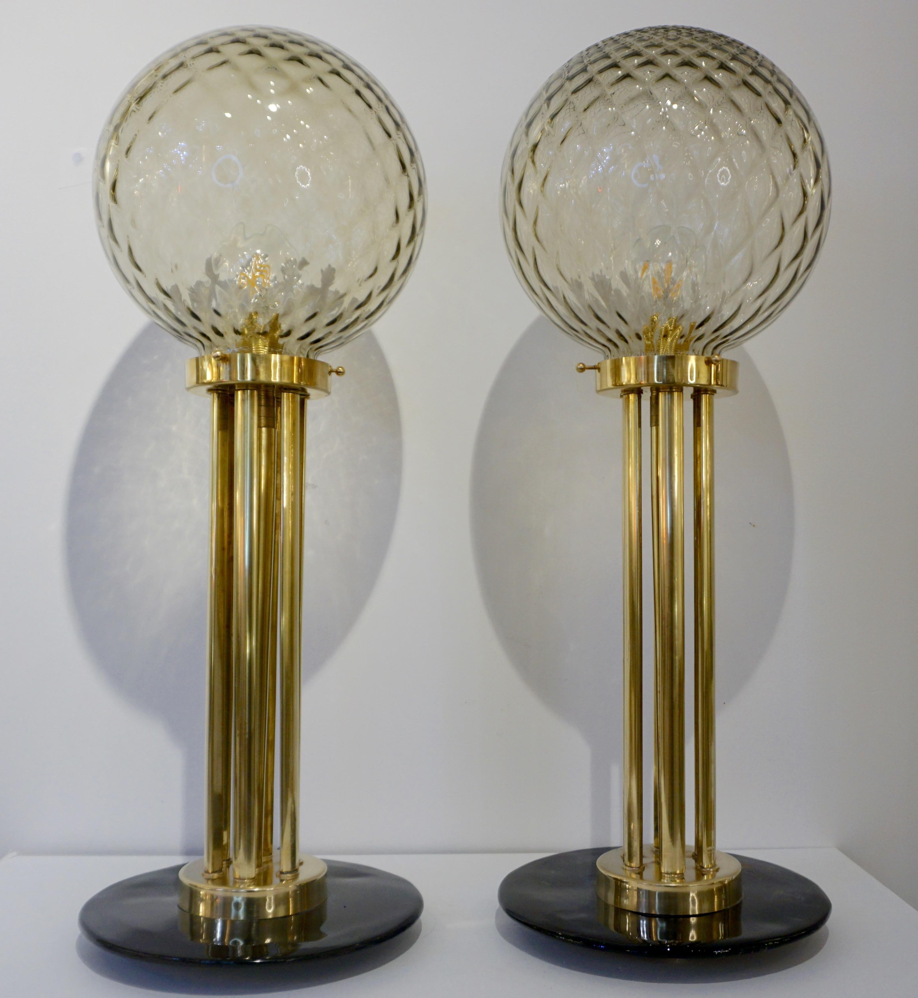A one-of-a-kind Venetian modern design pair of table lamps, entirely handcrafted in Italy with Art Deco style, circa 2010. The honeycomb blown Murano glass globes in gold amber color are supported by an organic column pedestal composed of 7 round
