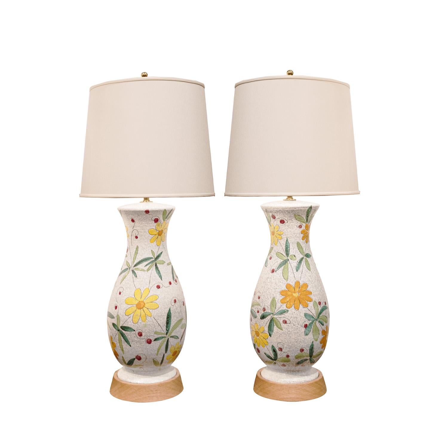 Pair of hand-made ceramic table lamps with flower motif on wood bases with polished brass hardware by Bitossi, Italy 1950's. These are beautifully made with wonderful coloration and execution.

Diameter: 8 inches
Height: 32 inches (adjustable to