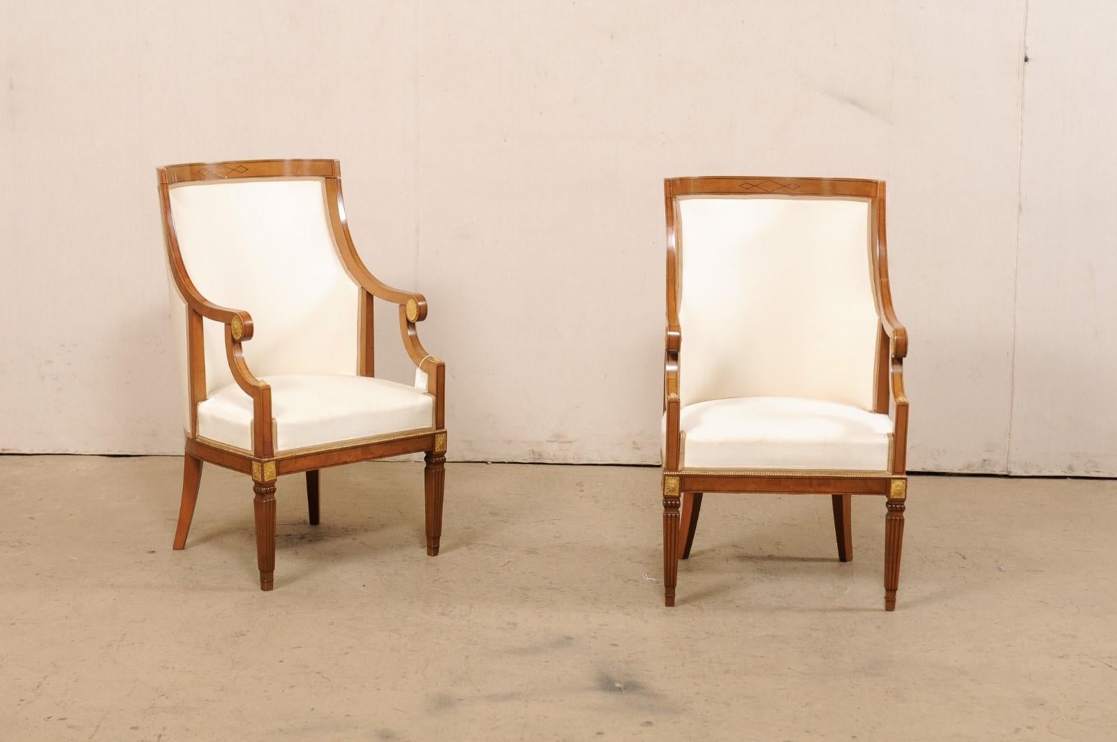 An Italian pair of carved wood armchairs, with upholstered back and seats, from the mid 20th century. This vintage pair of occasional chairs from Italy each have nicely rounded/barreled backs rest supports- upholstered and framed within a wooden
