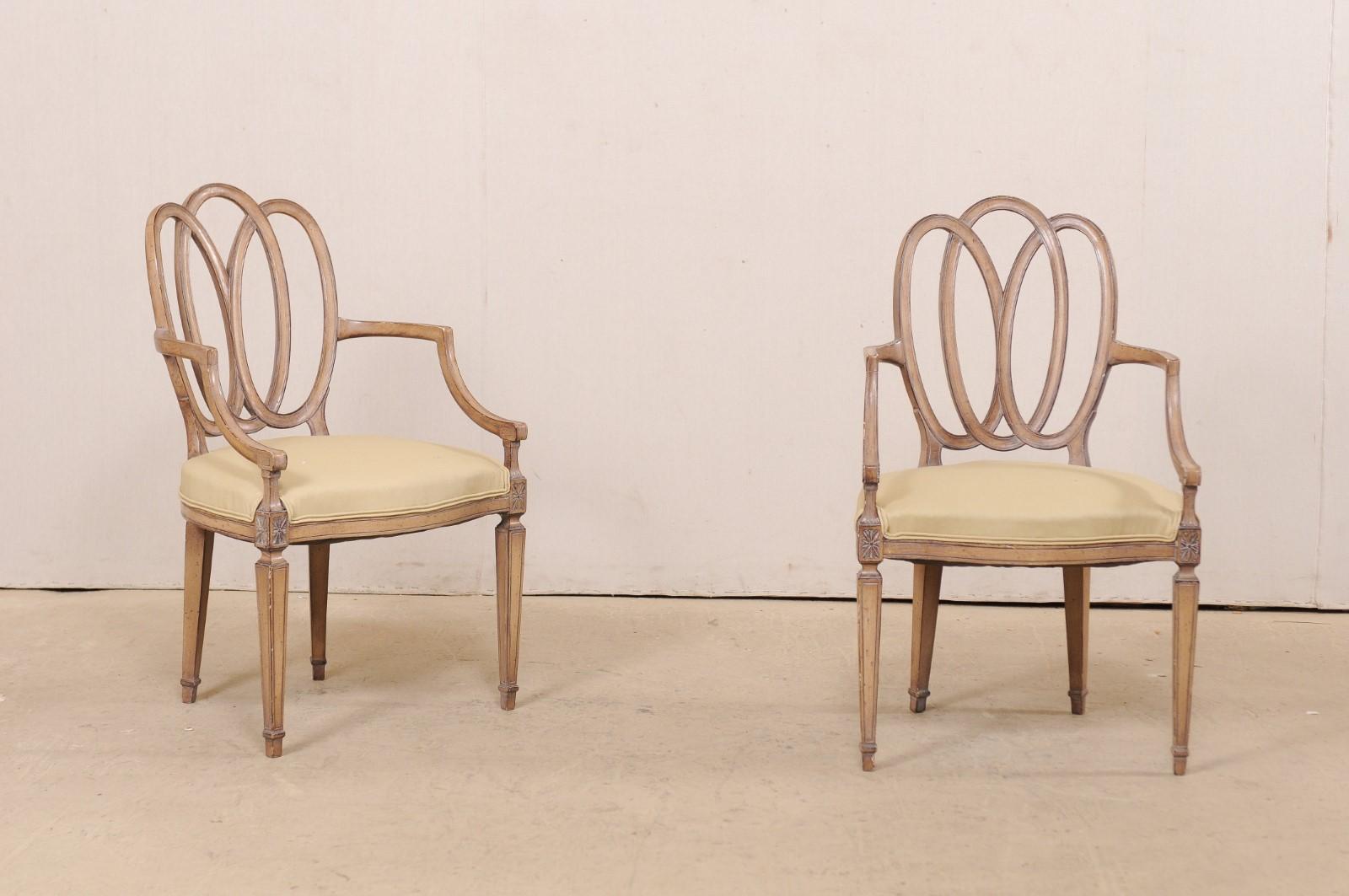 An Italian pair of carved wood armchairs with upholstered seats from the mid-20th century. This pair of occasional chairs from Italy have nicely entwined pierced oval-shaped backs, carved star accents adorn the apron at front seat rails, and they