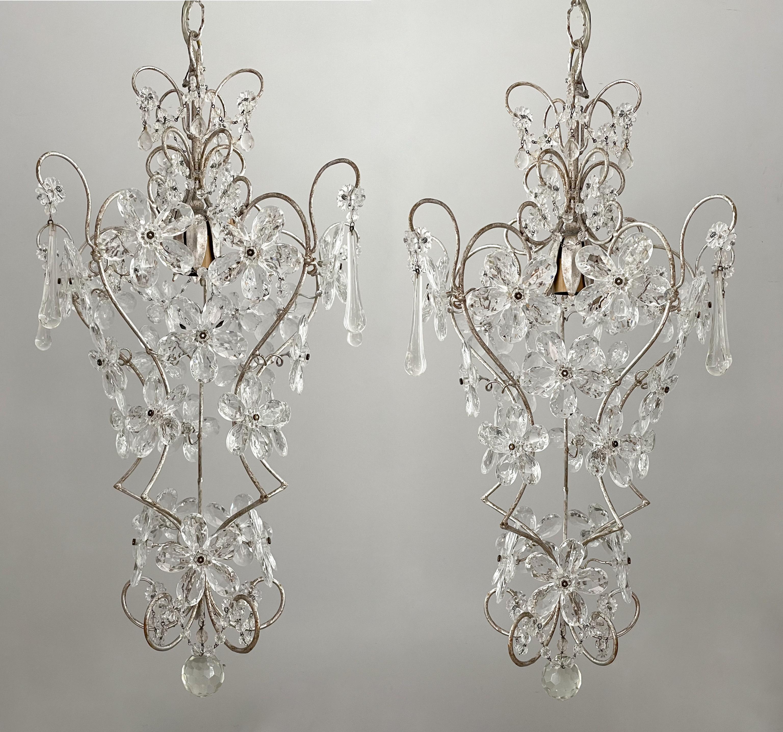 Magnifique paire de lustres italiens des années 1960 en fer et cristal perlé.

Chaque lustre se compose d'un cadre en fer à volutes, d'une finition à la feuille d'argent appliquée à la main et de fleurs faites de prismes de cristal à facettes. 

Les