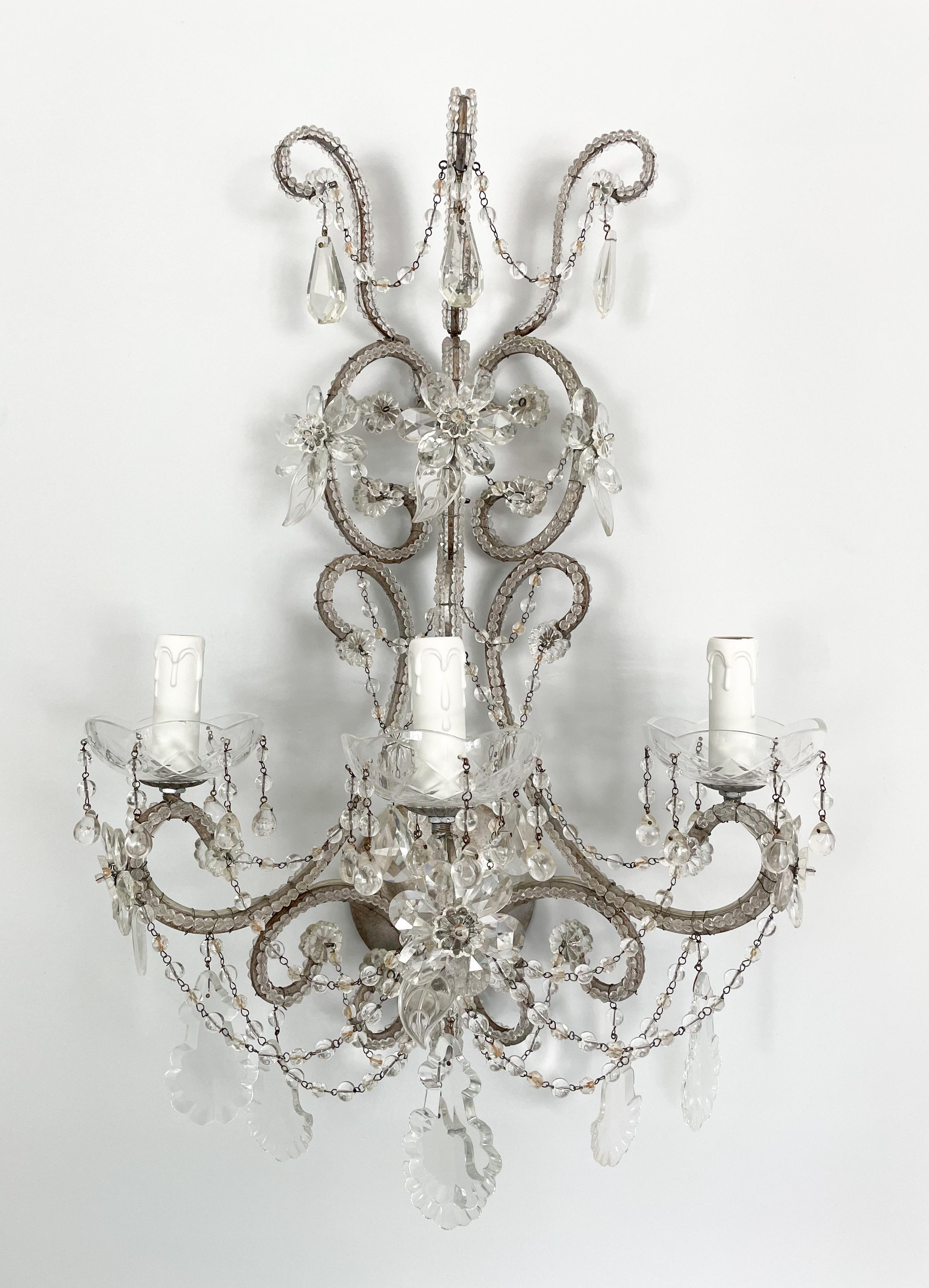 Glorious, pair of Italian crystal beaded sconces in the style of Maison Bagués. 

Each sconce consists of a scrolled silvered-iron frame outlined with “English cut” beads. Flowers and leaves made of cut glass along with French pendants complete