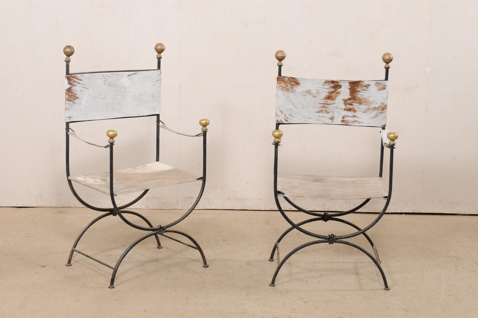 
An Italian pair of iron and hide curule chairs from the mid 20th century. This vintage pair of curule chairs from Italy are also commonly called savonarola, which are defined by their signature semi-circular frames where the upper frame adjoins to