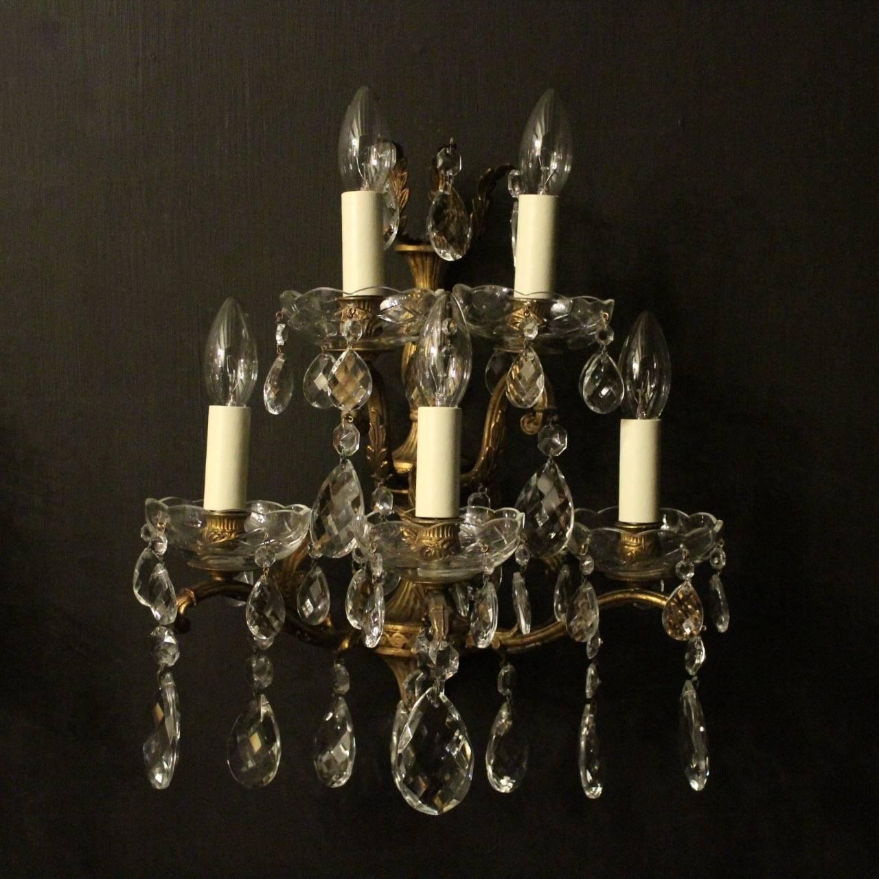 A large Italian pair of gilded cast bronze and crystal five-arm double tiered antique wall lights, the leaf scrolling arms with glass bobeches drip pans and bulbous leaf candle sconces, issuing from a foliated elongated backplate with leaf canopy