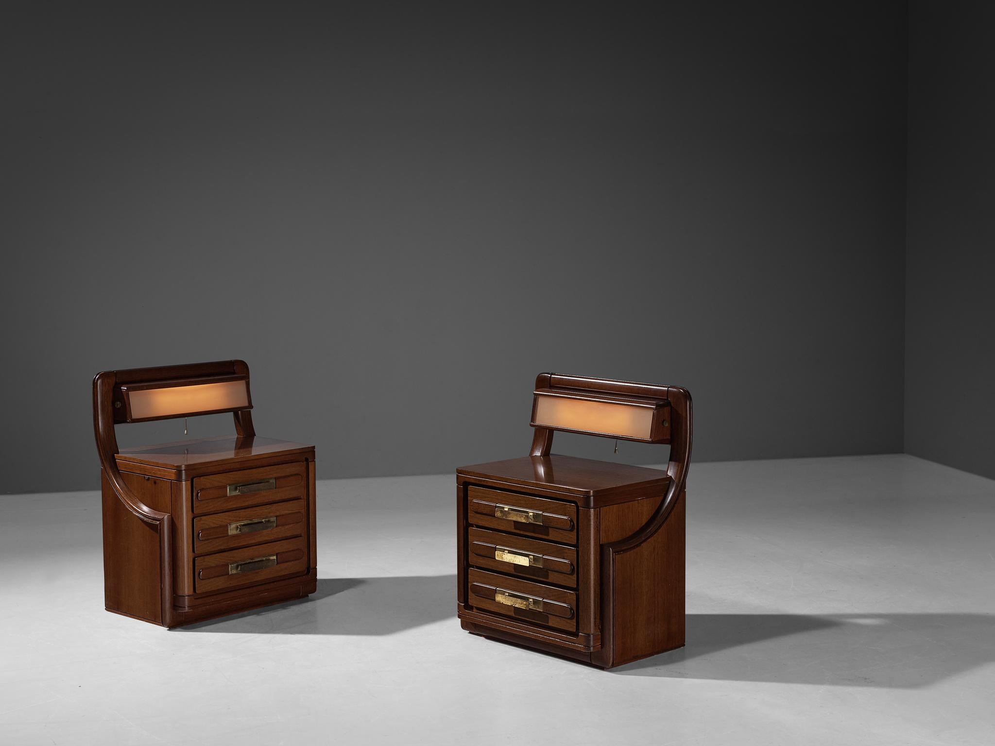 Pair of nightstands, teak, glass, brass, Italy, 1970s.

Charming and chic pair of nightstands made in teak and veneer. The upper part of the nightstands has flattering integrated lighting that shines through a pink matte glass cover. They have