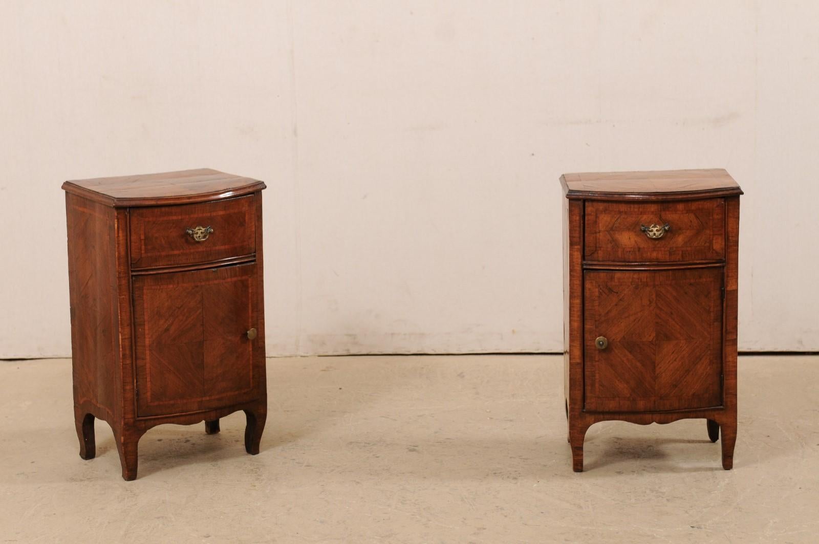 An Italian pair of small-sized bow-front wooden side cabinets from the turn of the 18th and 19th century. This antique pair of commodini from Italy are each adorn in lovely wood banding and inlay, and feature a bow-front top over case with matching