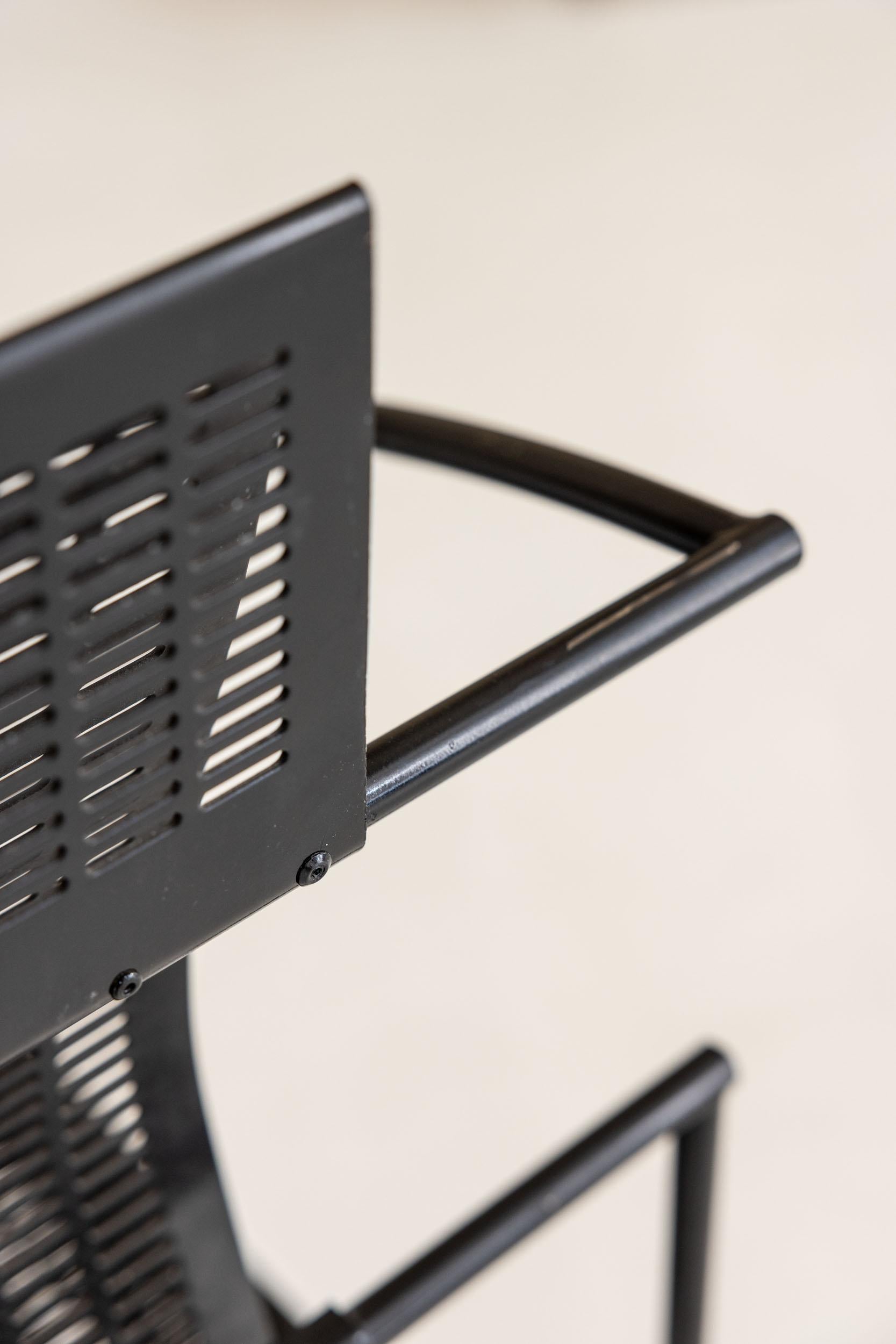 Pair of chairs mod. Quinta 605 in metal. The seat and back are made of a black lacquered micro-perforated metal plate with glossy finish. The geometric structure that makes up the armrests and legs is given by a black lacquered metal rod with glossy