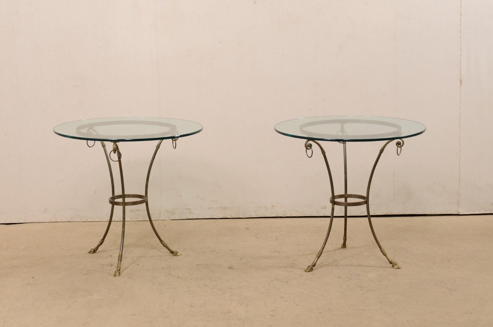 Paire de tables d'appoint italiennes vintage avec plateau en verre et cadre en laiton. Cette paire de tables italiennes des années 1970 présente chacune un plateau de verre rond de 30 pouces, placé dans un cadre en laiton composé de trois pieds,