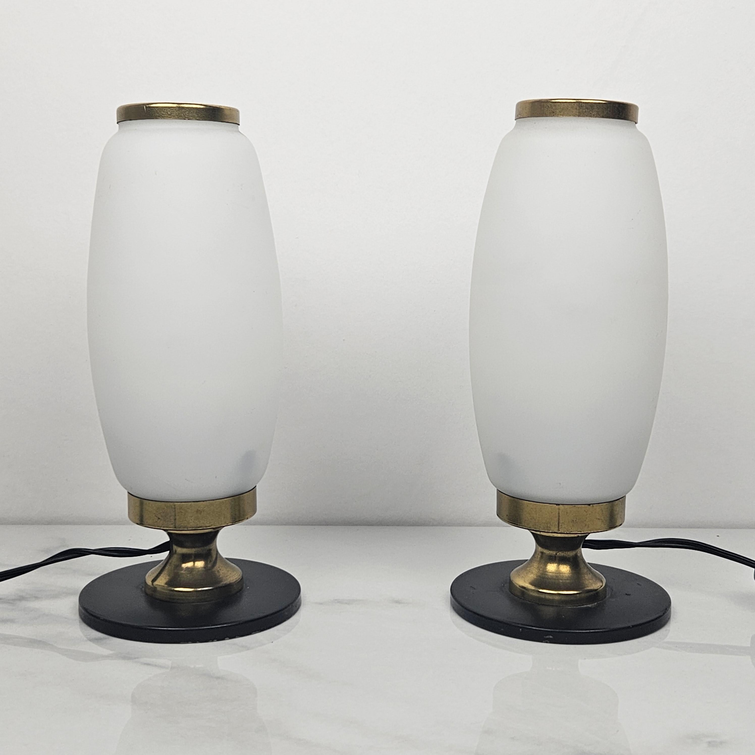 Very cute set of 2 small opaline glass table or bedside lights.
This set if fabricated in Italy in the 1950's.

They are made in the style of Stilnovo.

The base is made of brass and metal. 
The lampshade is made of opaline glass.

Bulb
